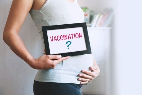 A pregnant woman holding up a sign that says Vaccination?