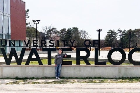 Luca Roy standing in front of the University of Waterloo sign