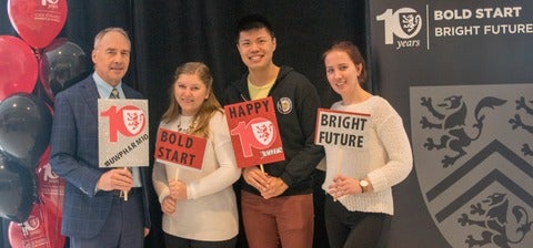 Dave Edwards and 3 students smiling with Bold Start and Bright Future signs.