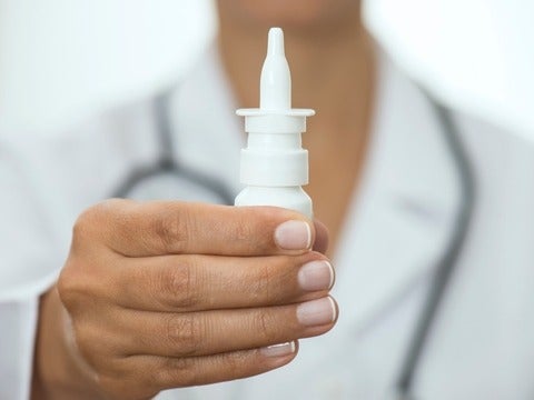 A hand holding up a nasal spray bottle