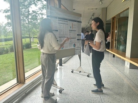 A student pointing to a scientific poster explaining to another person