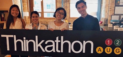 Two Think Research employees with Rui Su and Kelvin Yam holding a Thinkathon sign