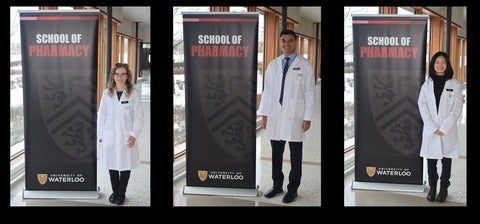 Three class of 2024 students standing in front of a banner in their new white coats