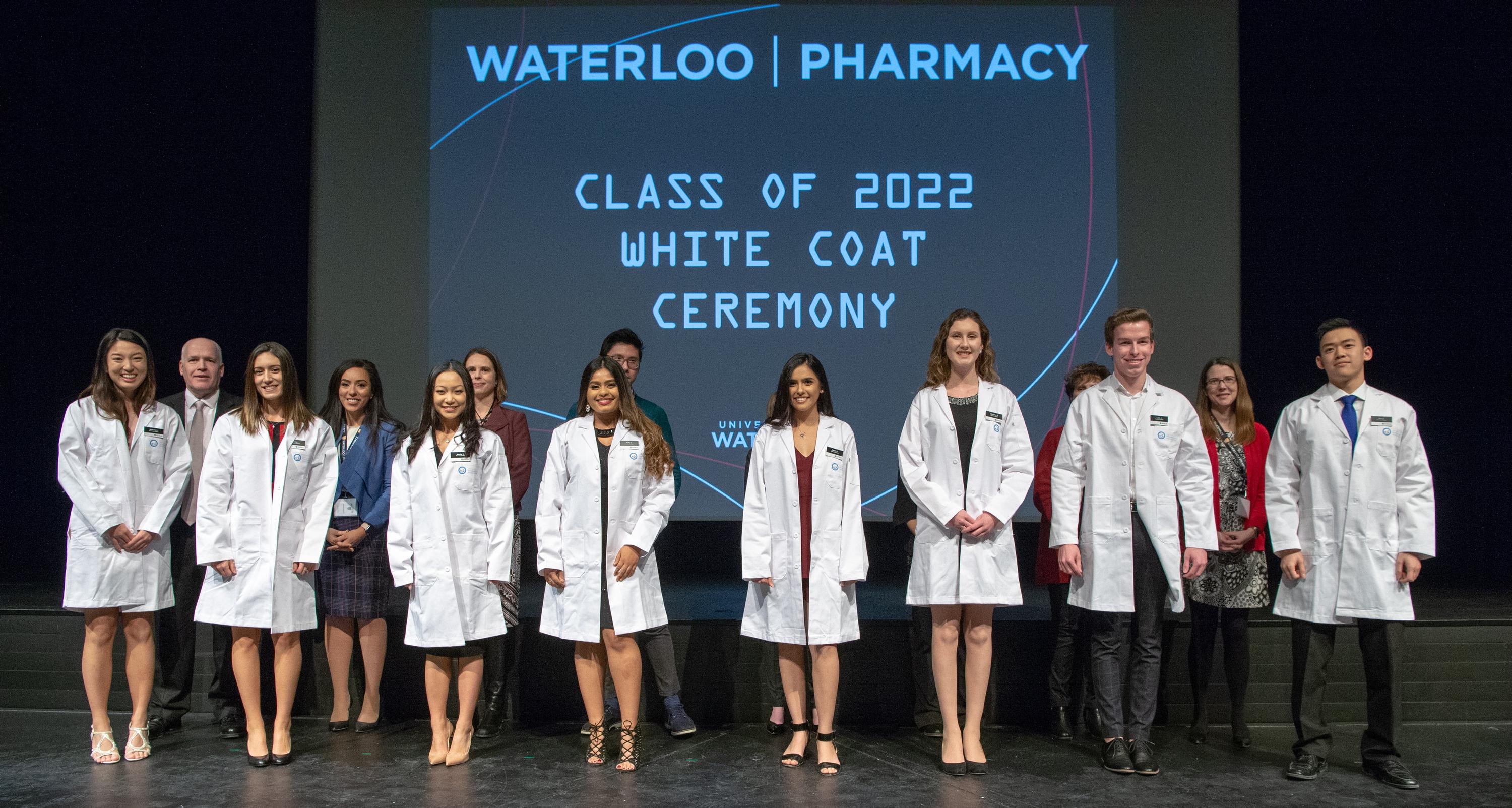 8 students recieving robes on stage at white coat ceremony