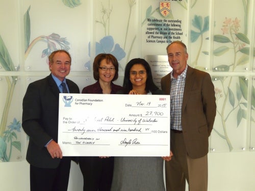 Professor Patel receiving research grant from Canadian Foundation of Pharmacy individuals standing in lobby with large cheque