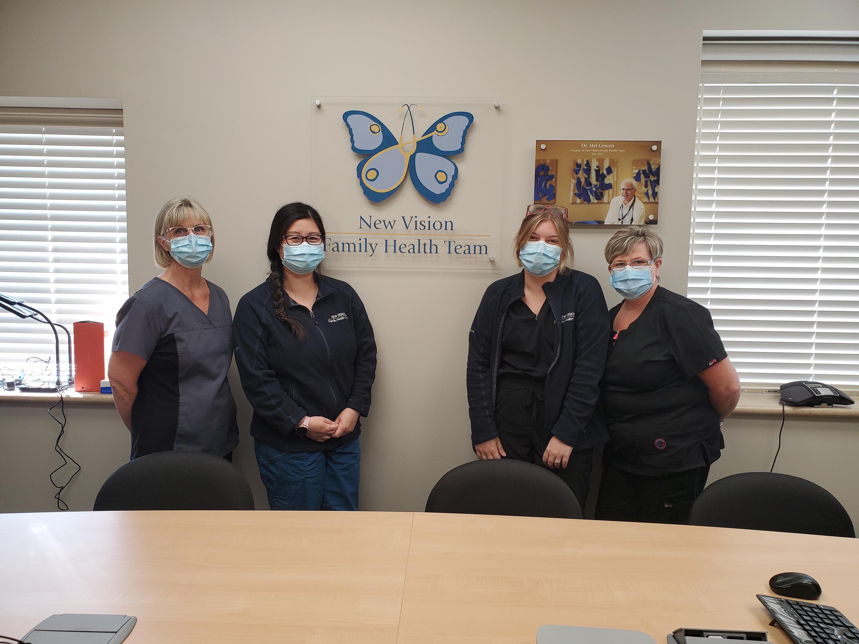 the team at New Vision Family Health Team wearing masks and standing in a conference room