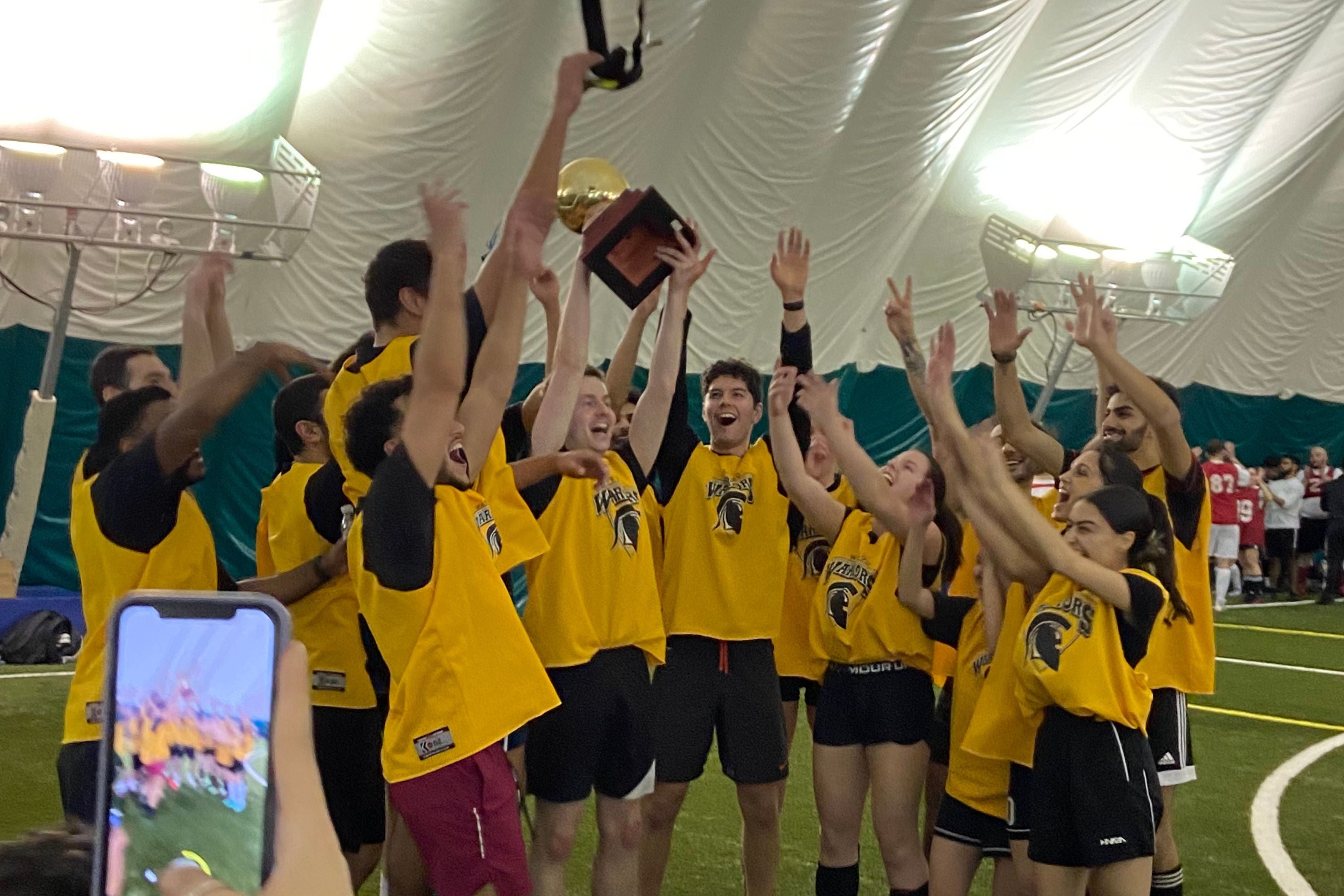 A group of students cheering and celebrating a soccer game win