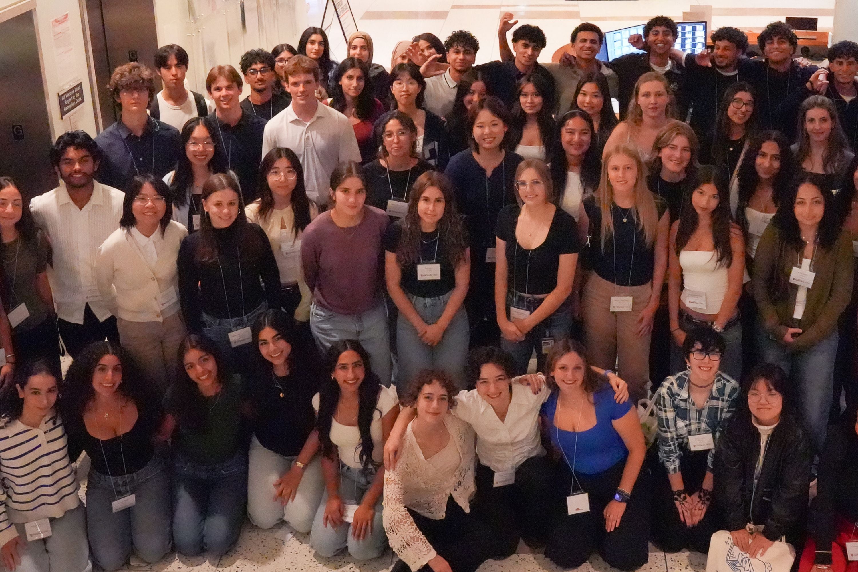 A large group of students smiling in a lobby