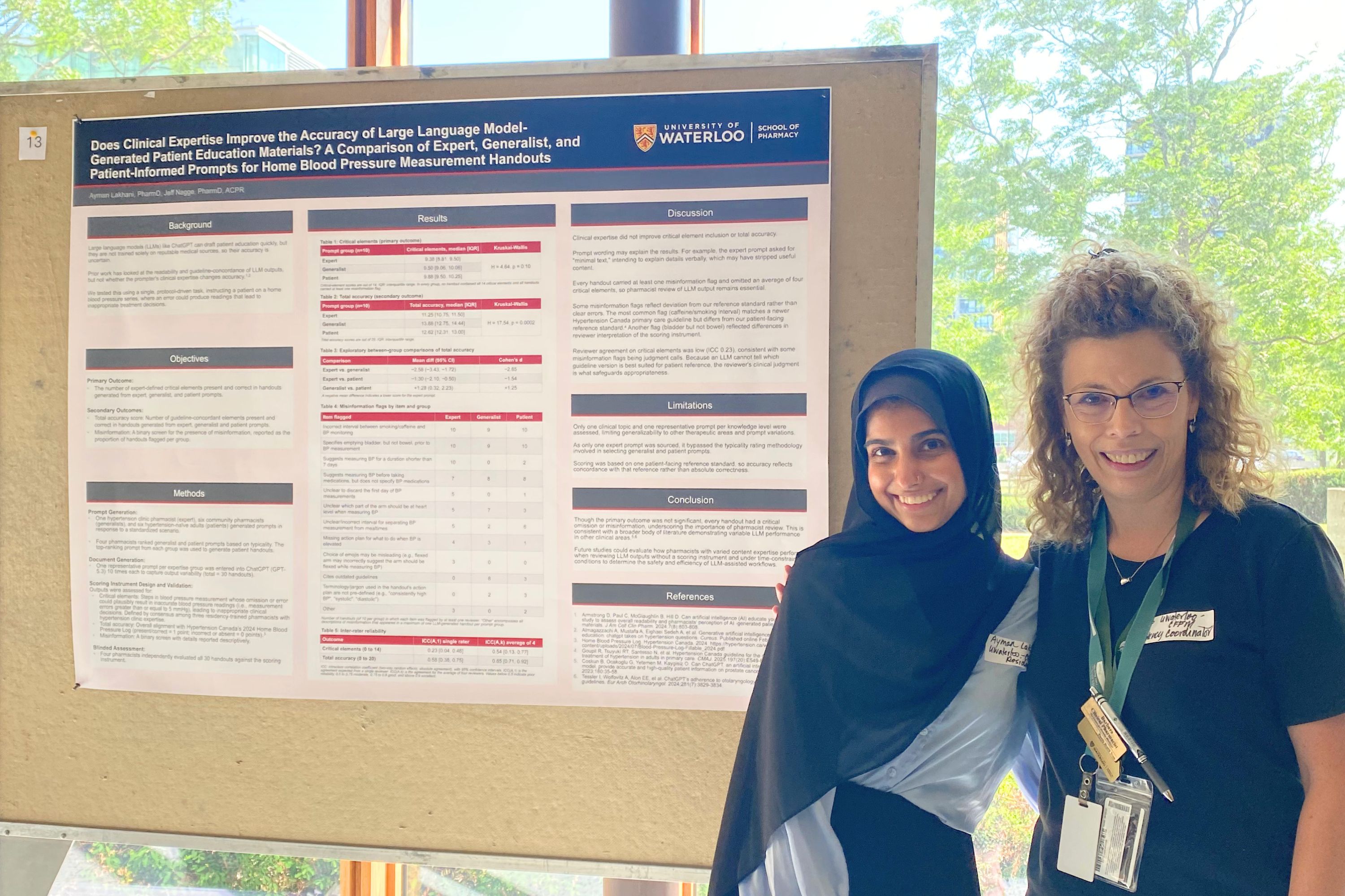 A presenter and preceptor stand beside a research poster at a scholarly poster session. The poster, displayed on a presentation board, summarizes a University of Waterloo School of Pharmacy study on the accuracy of AI-generated patient education materials. Large windows and trees visible outside provide a bright backdrop to the event.