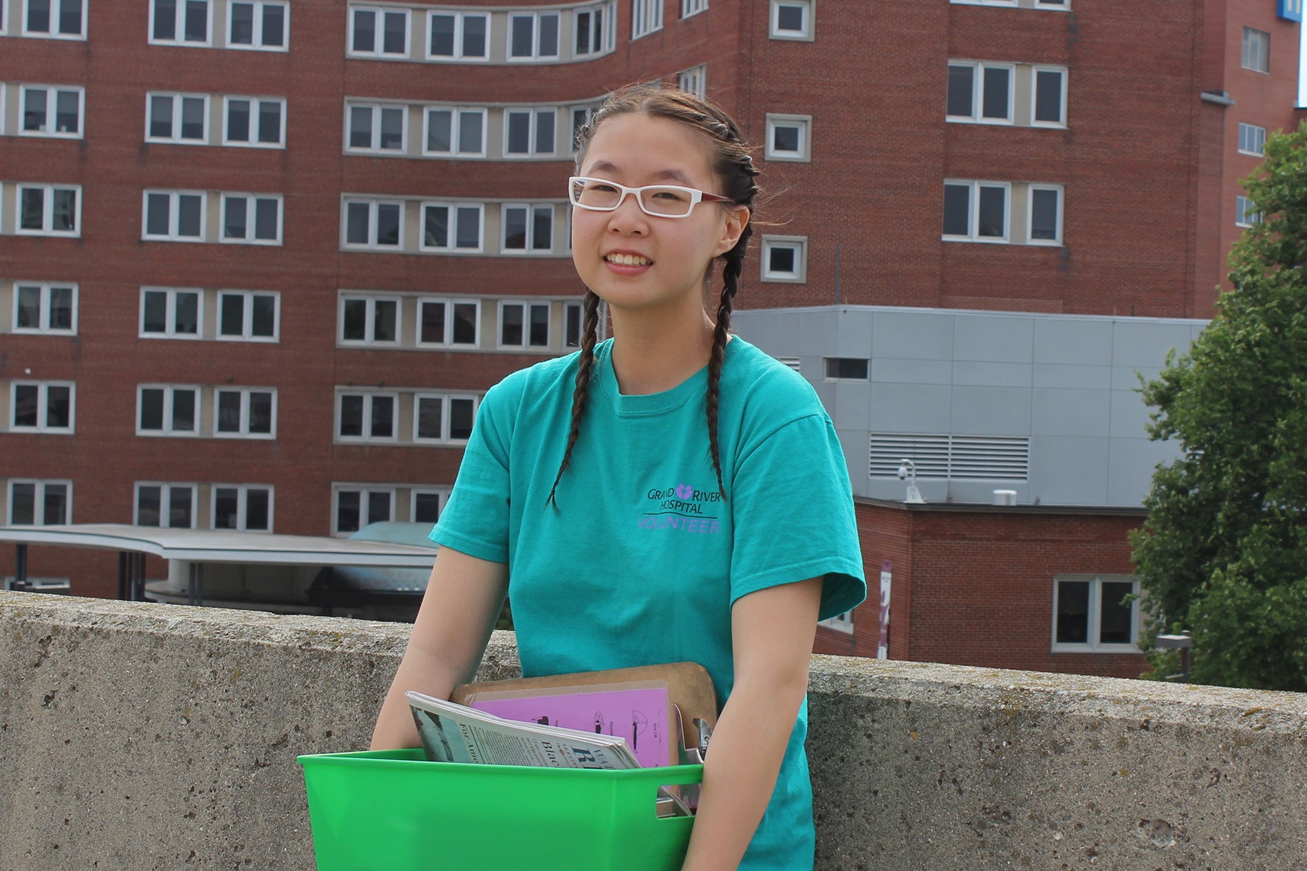 Woman holding green bin of supplies