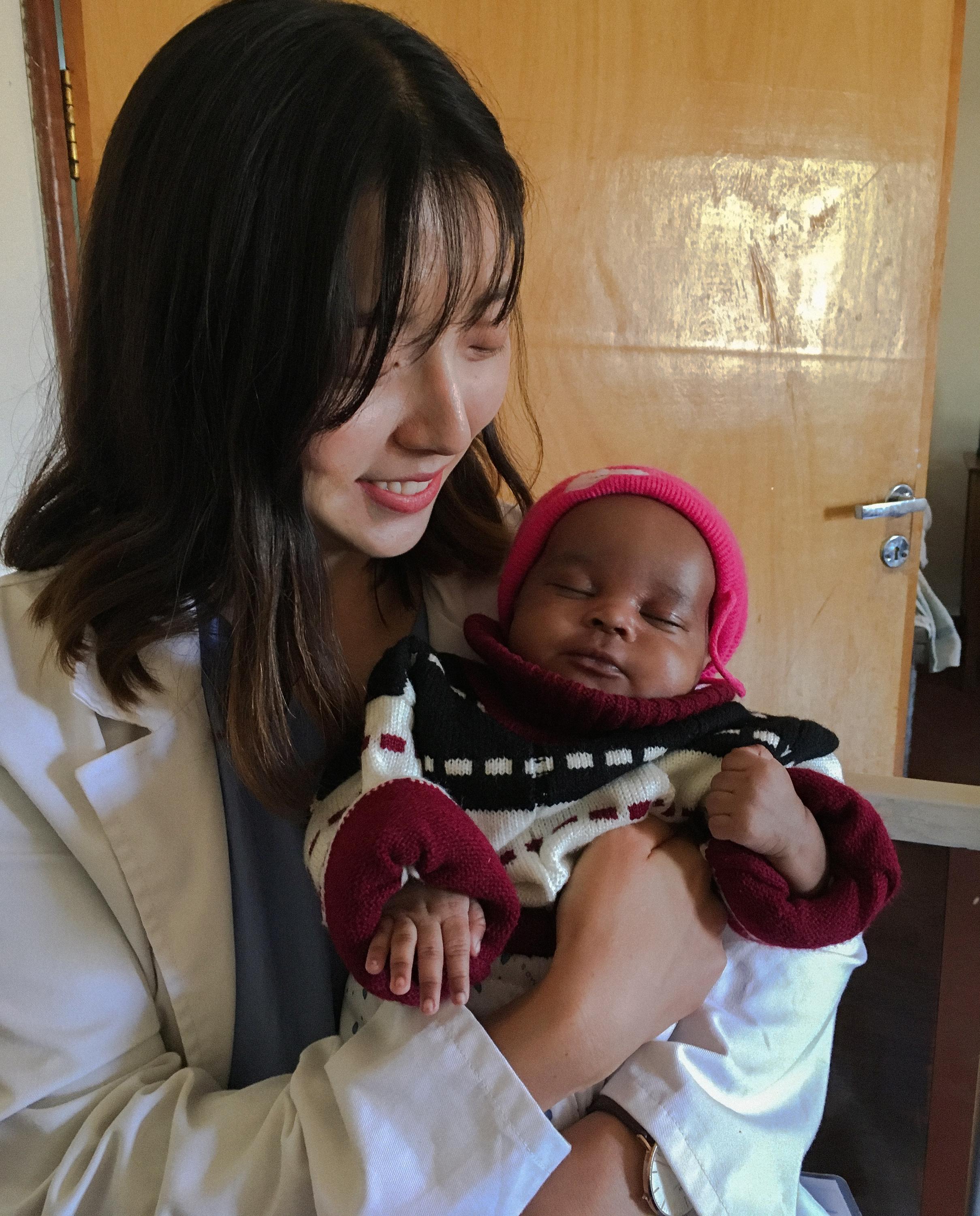 Jung In Kim holding a infant patient in Tanzanian hospital