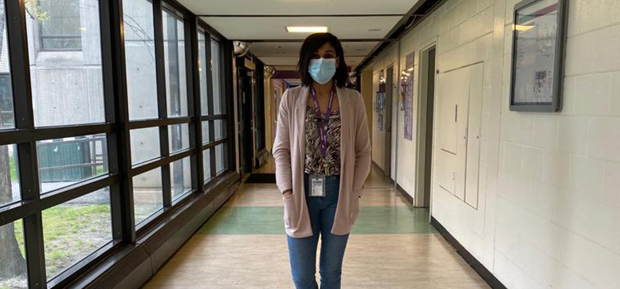 Aman wearing a mask and standing in a hallway at CAMH