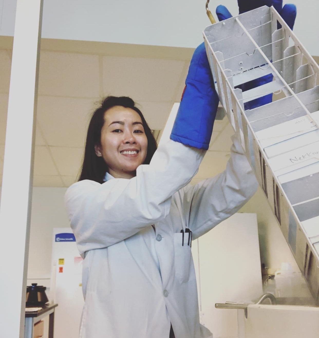 Amy Pham in the lab holding a piece of lab equipment