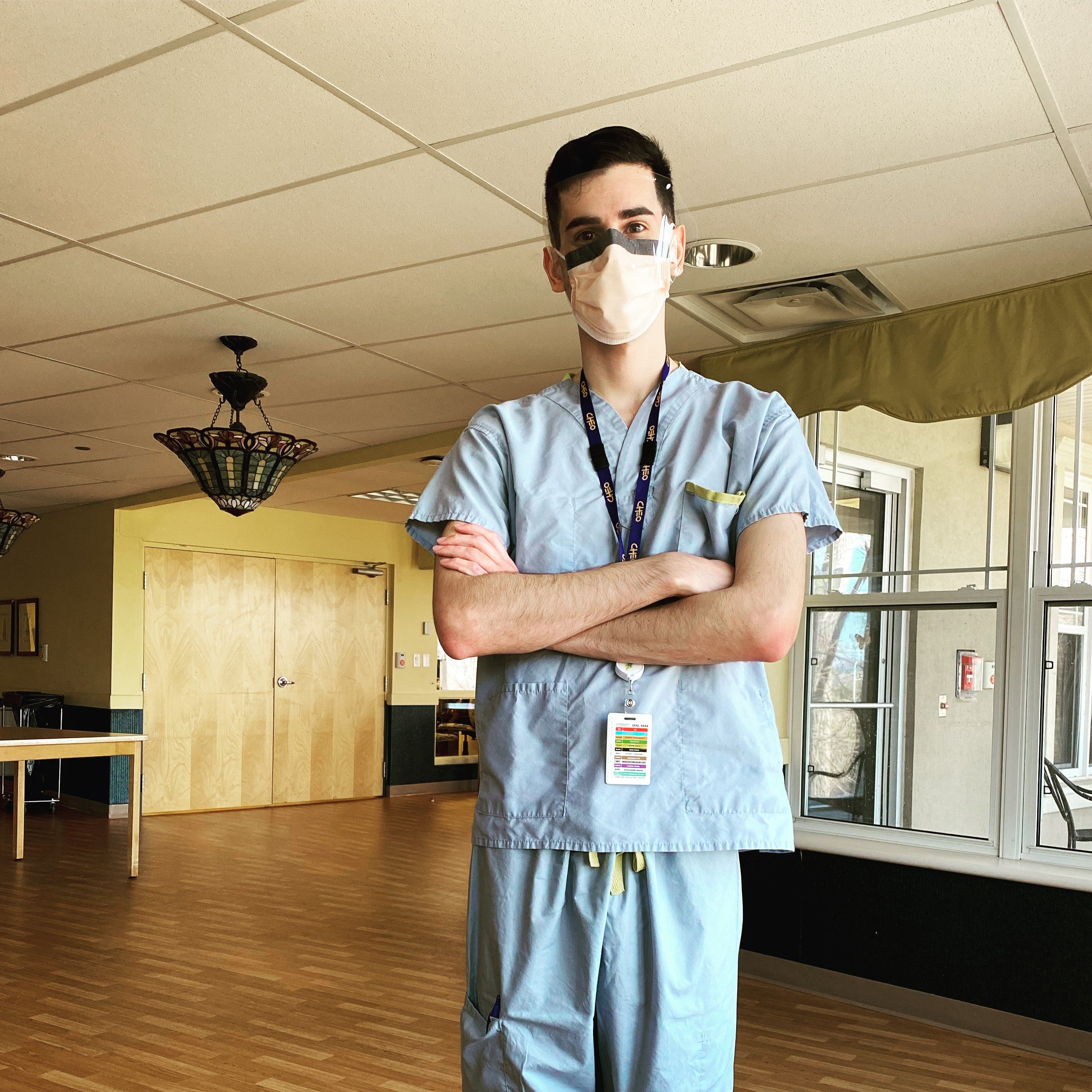 Brad Murphy in scrubs and a mask with his arms crossewd