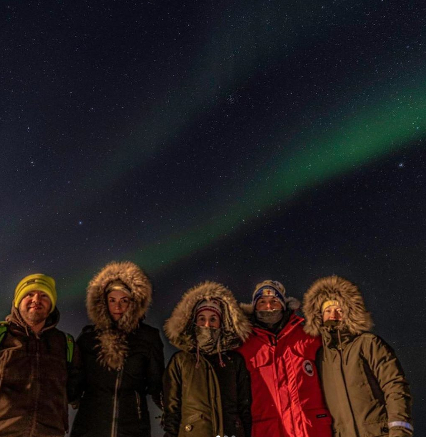 Jenna, Chris and friends stand in front of the northern lights