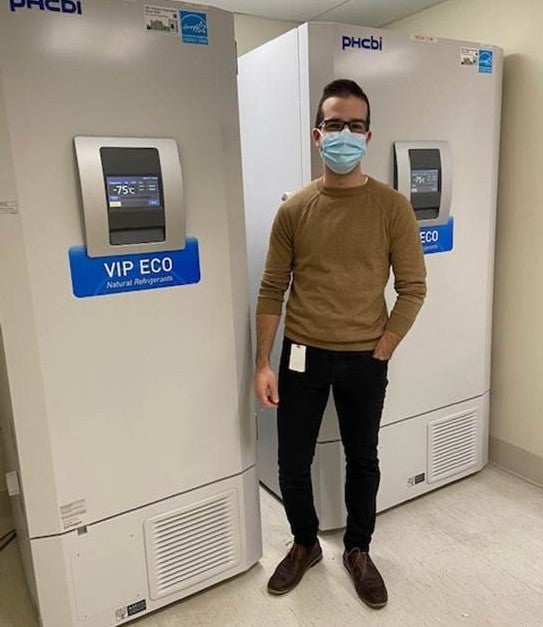 Daniel Pereira standing in front of freezer at vaccine clinic
