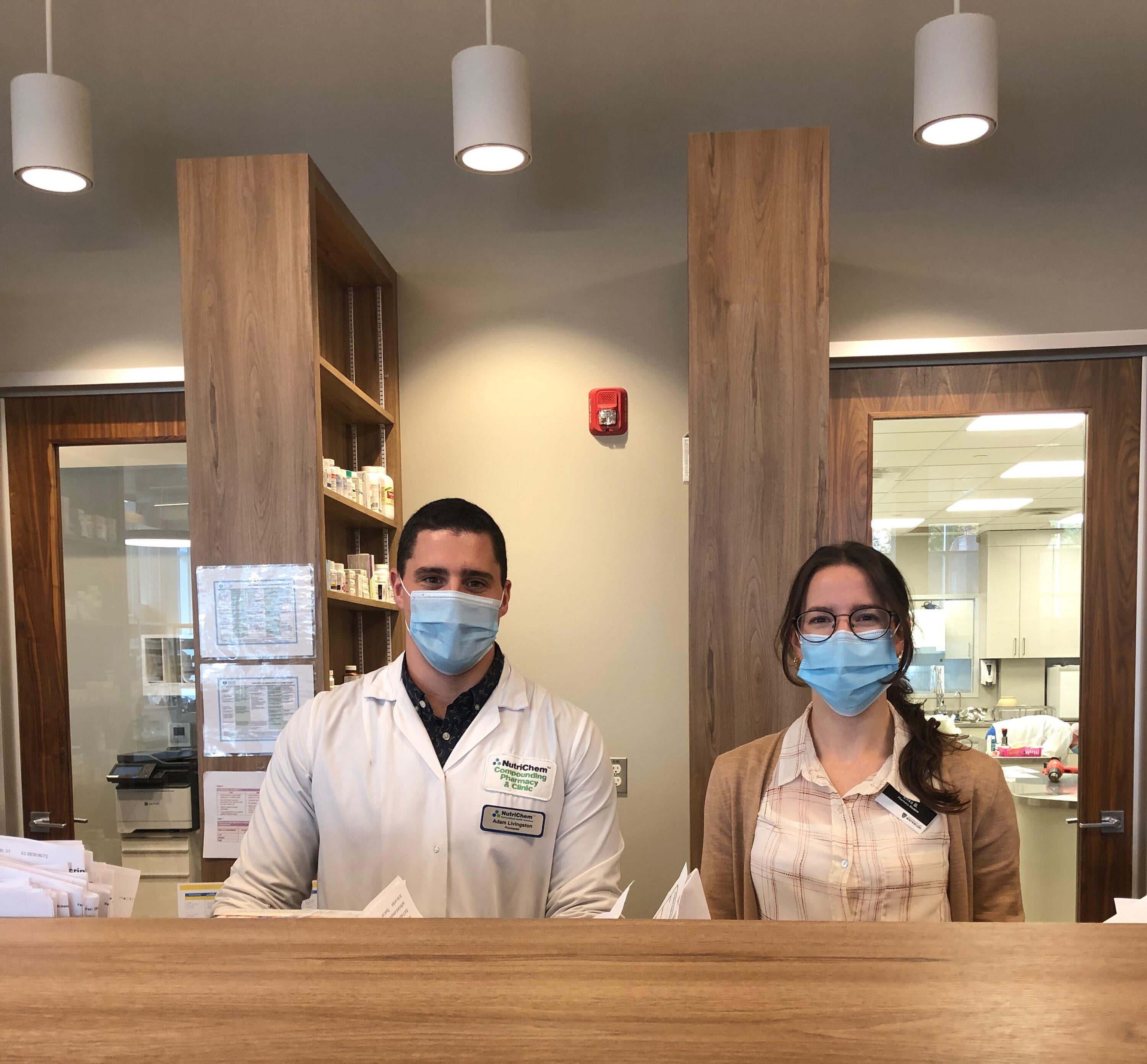 Adam and Elisa behind the dispensary wearing masks at the NutirChem Pharmacy