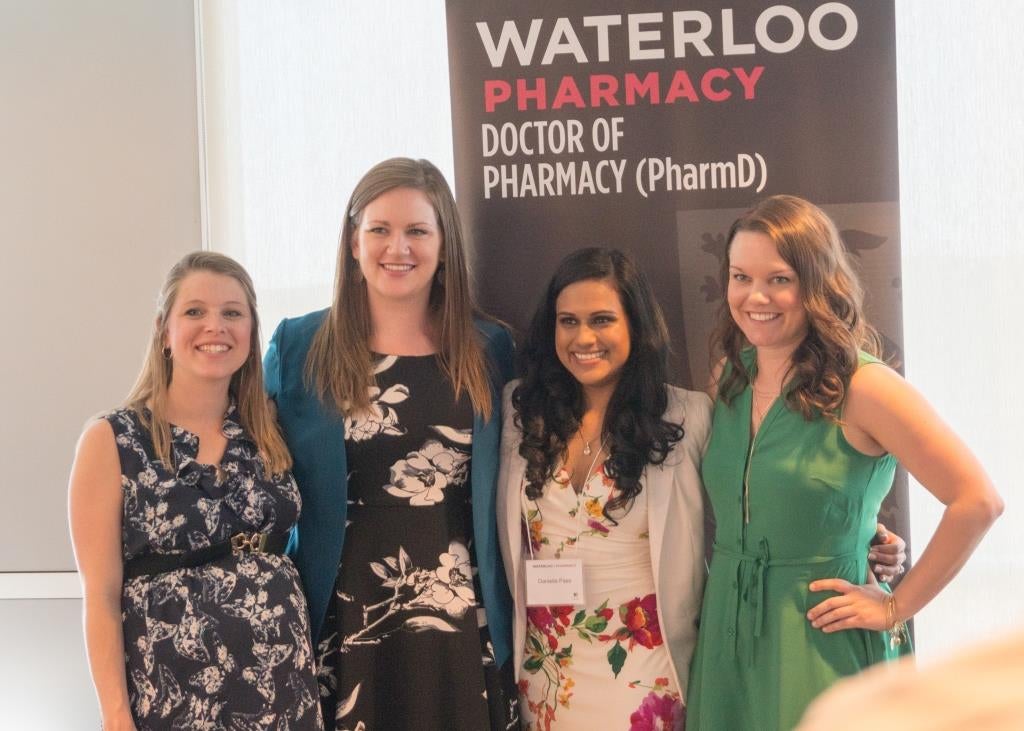 Four bridging students standing in front of a banner that says Waterloo Pharmacy Doctor of Phamracy (PharmD)