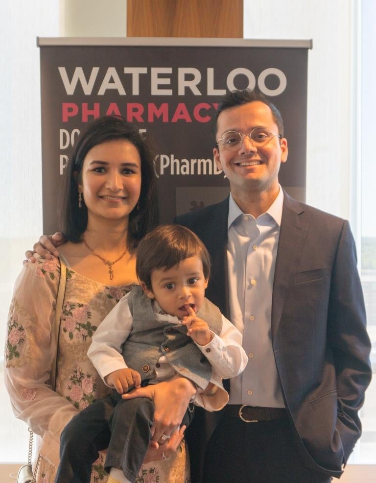 A graduate and her family in front of a Waterloo Pharmacy banner