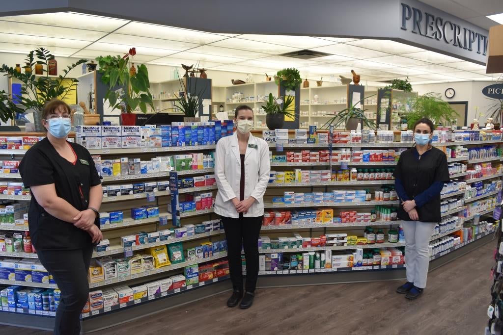 Jeannine and her team standing separated and wearing masks inside the pharmacy