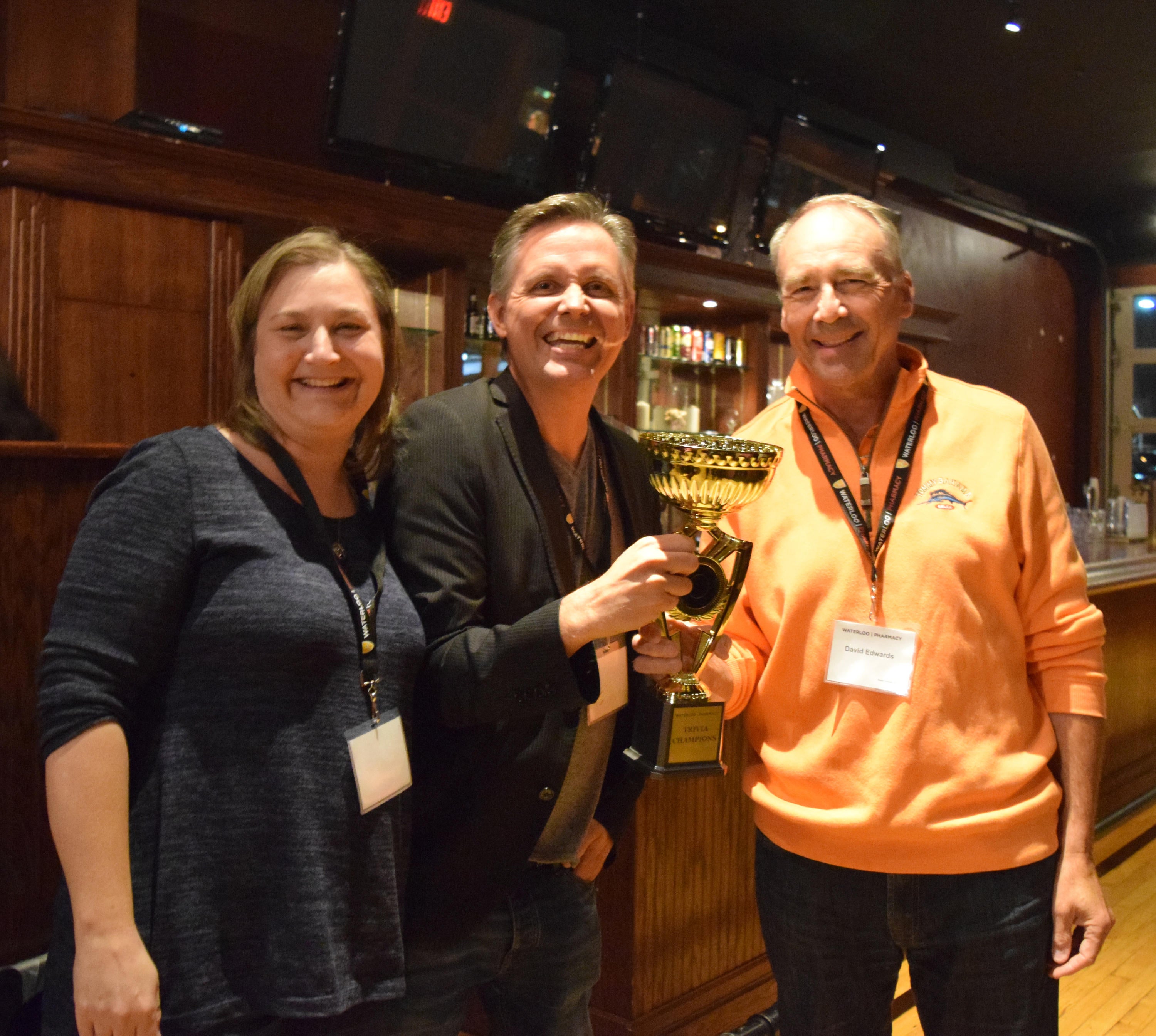 Three people holding trivia trophy