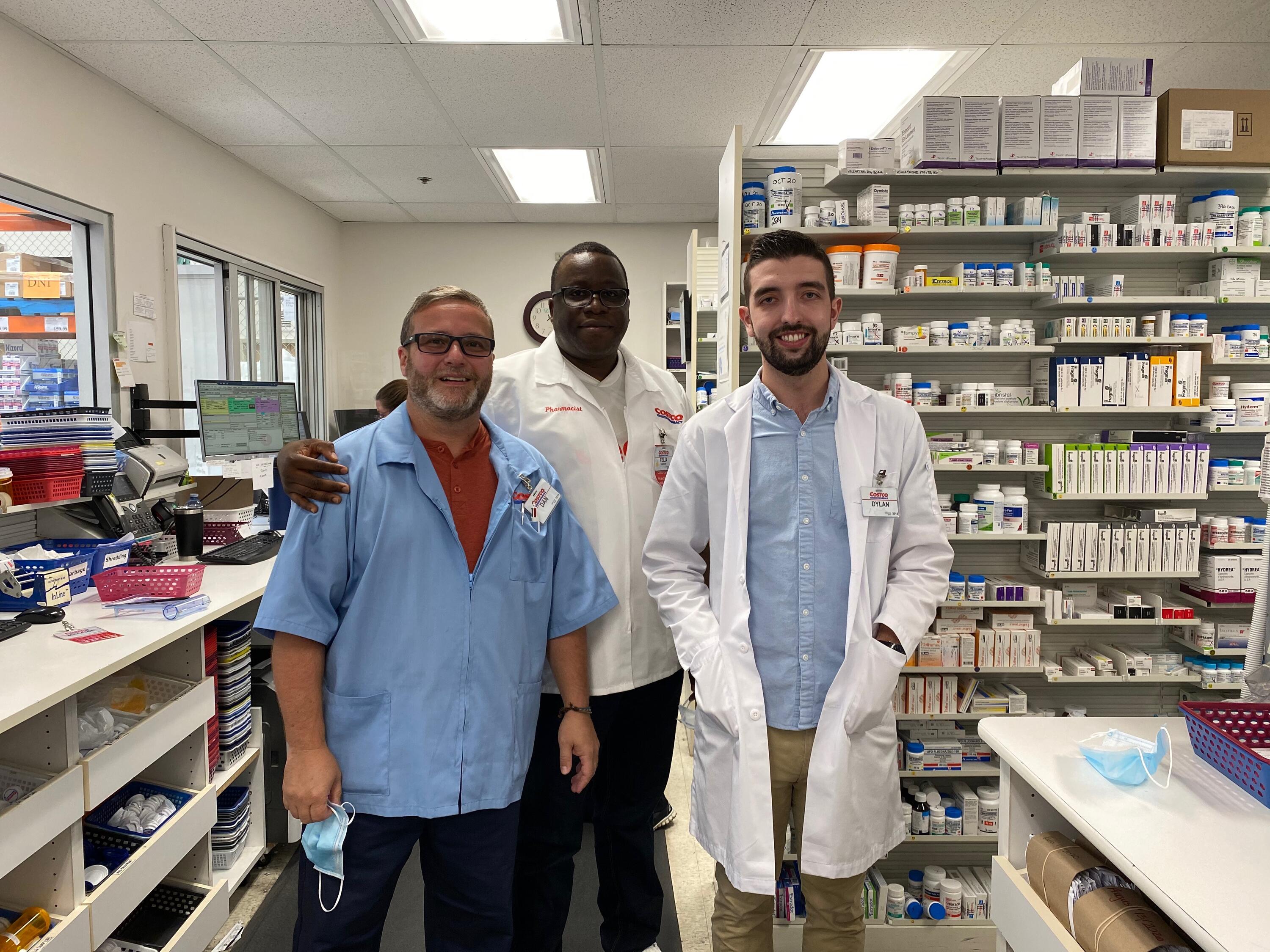 A coworker with Dylan and his supervisor standing in the pharmacy smiling
