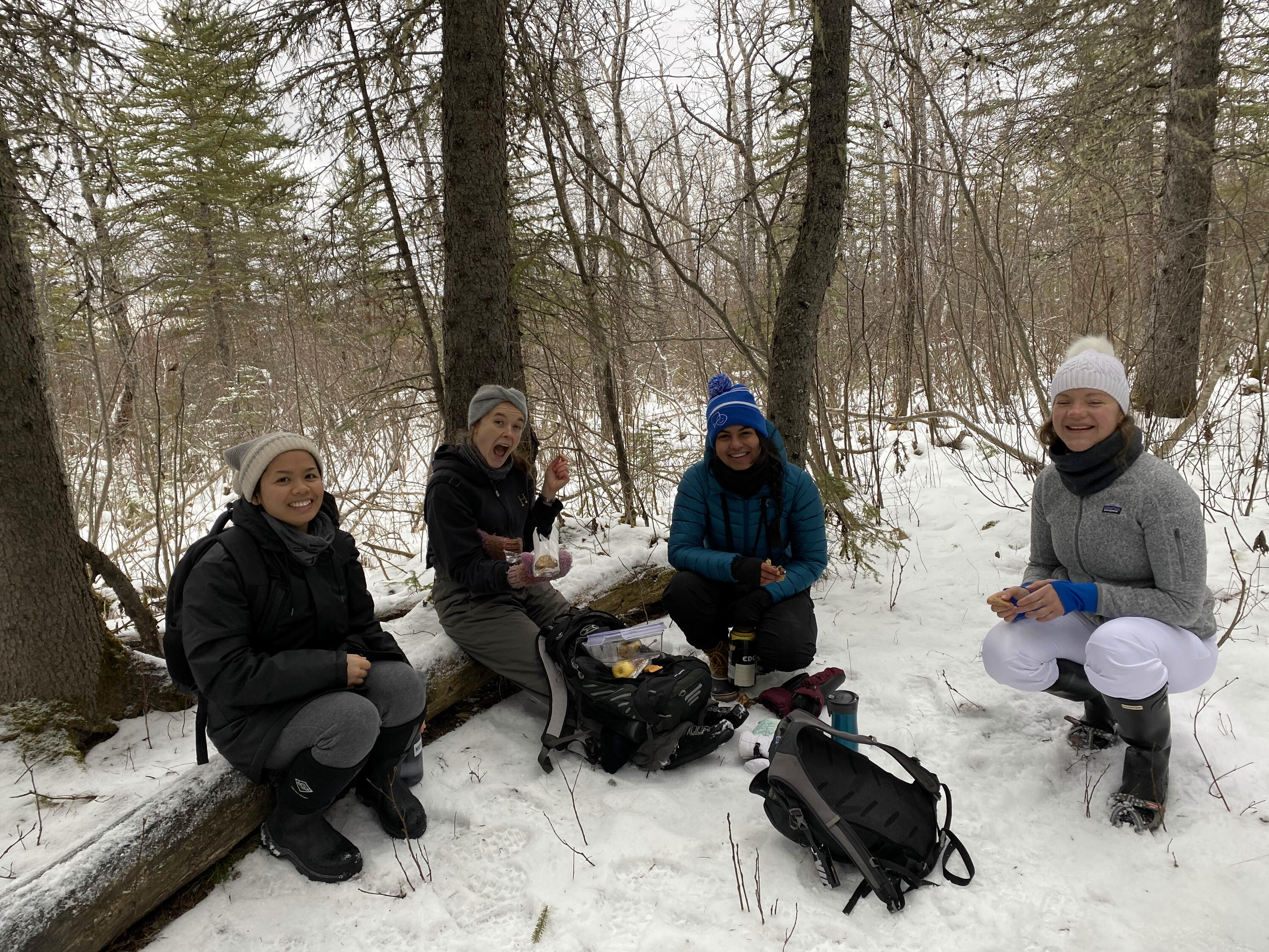 Celine sitting on a log with other students in the snow