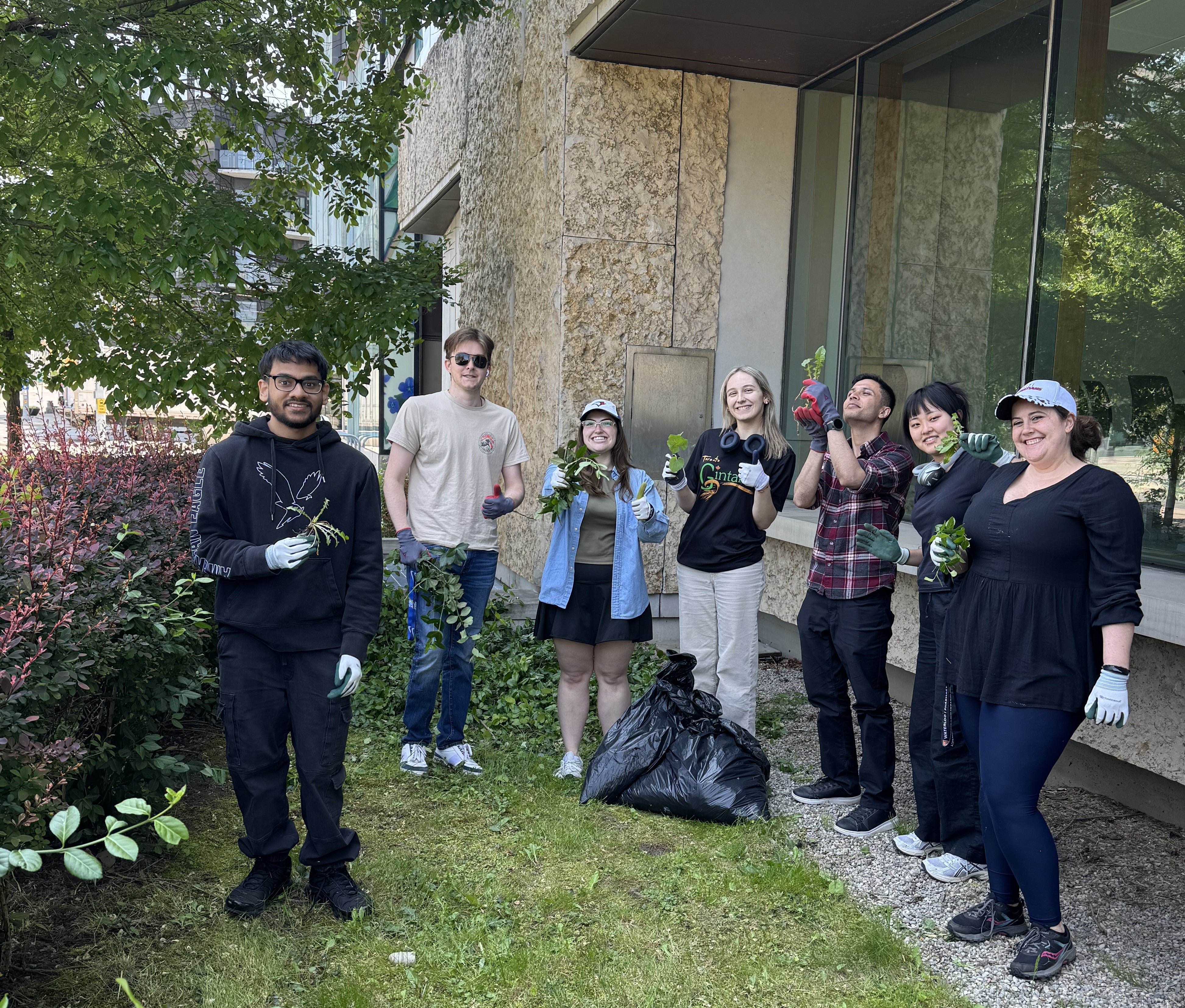 A group of people smiling holding plants