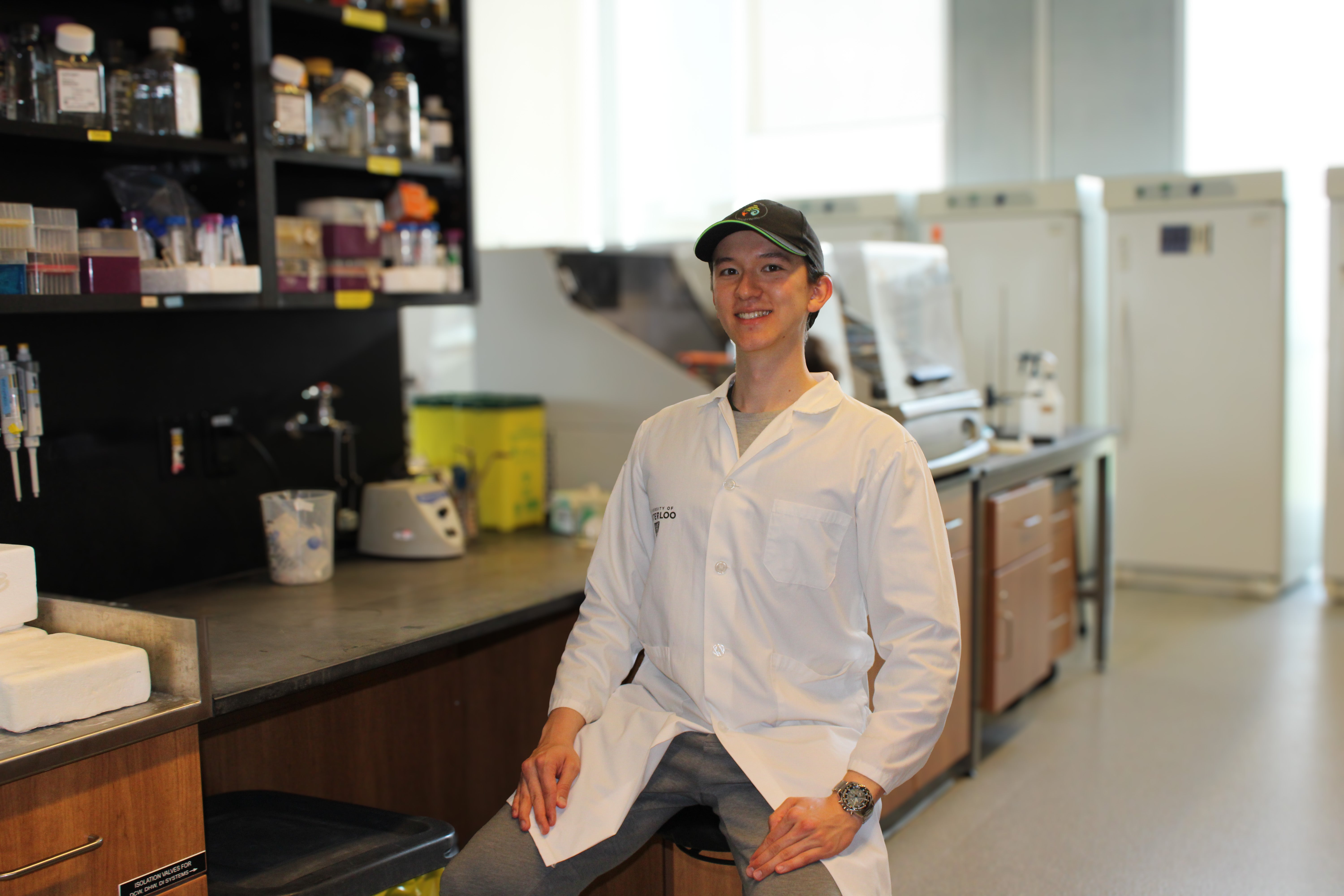 Nicholas Cheng sitting in a lab in a white coat