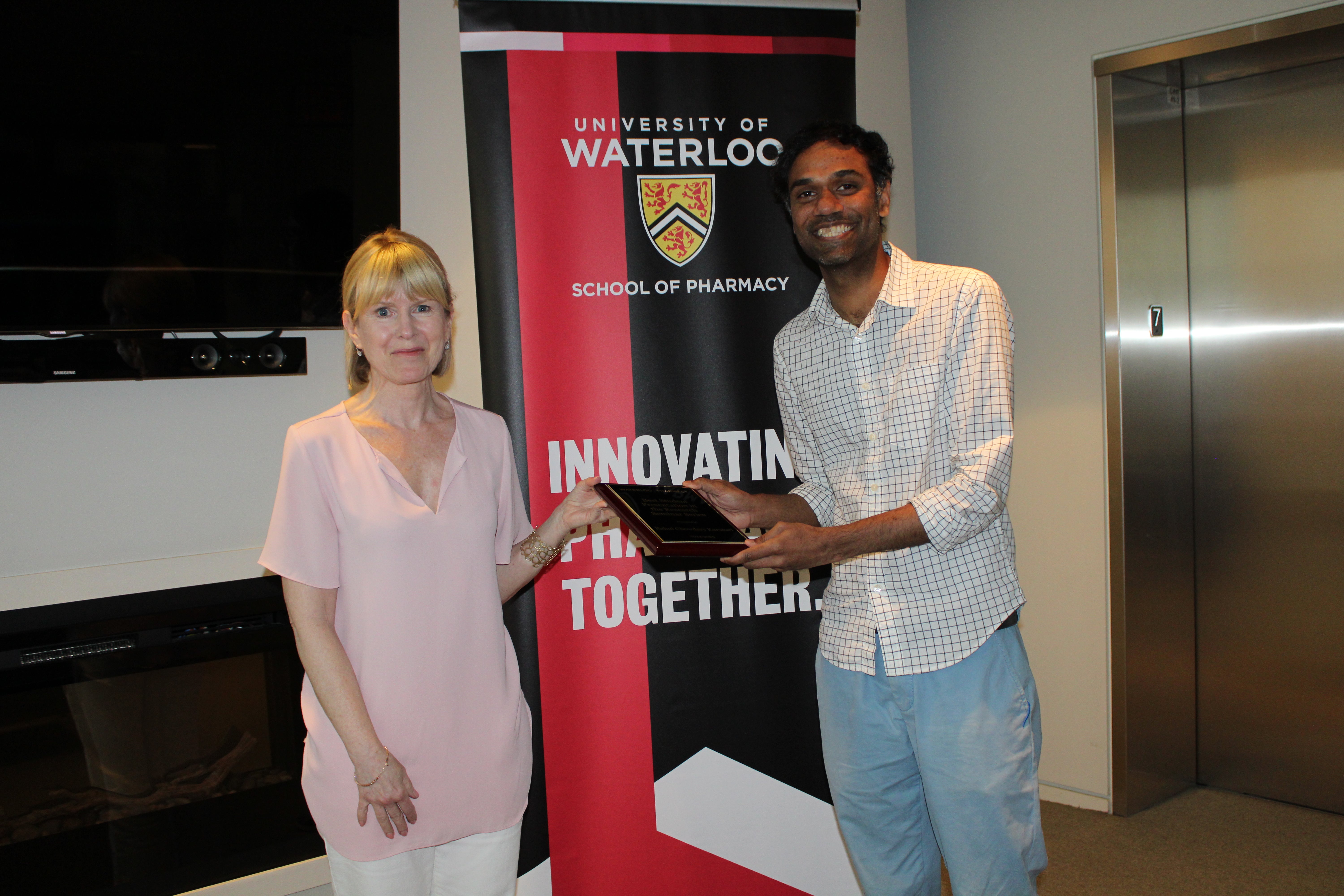 Two people smiling holding an award
