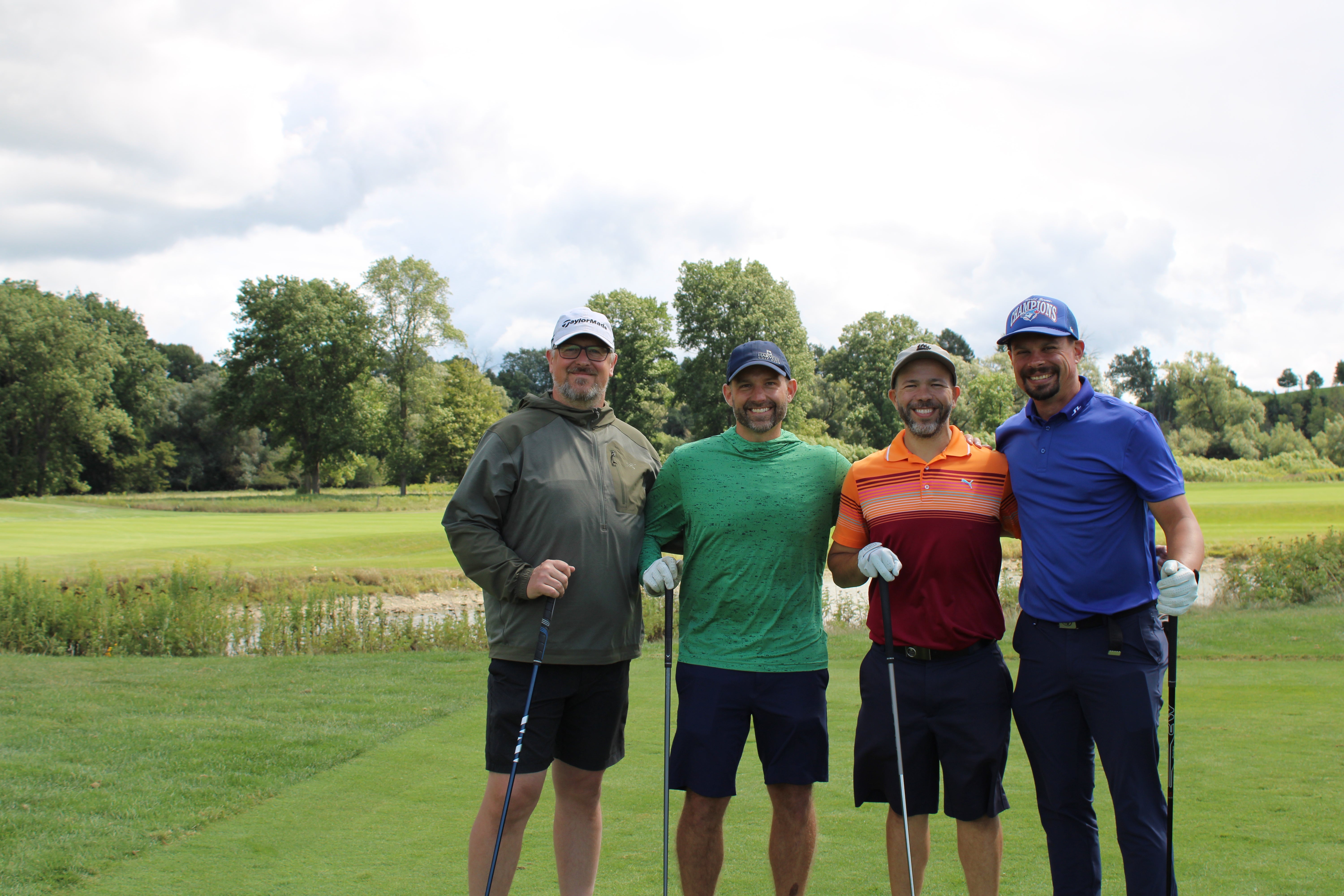 A foursome of men on the golf course smiling