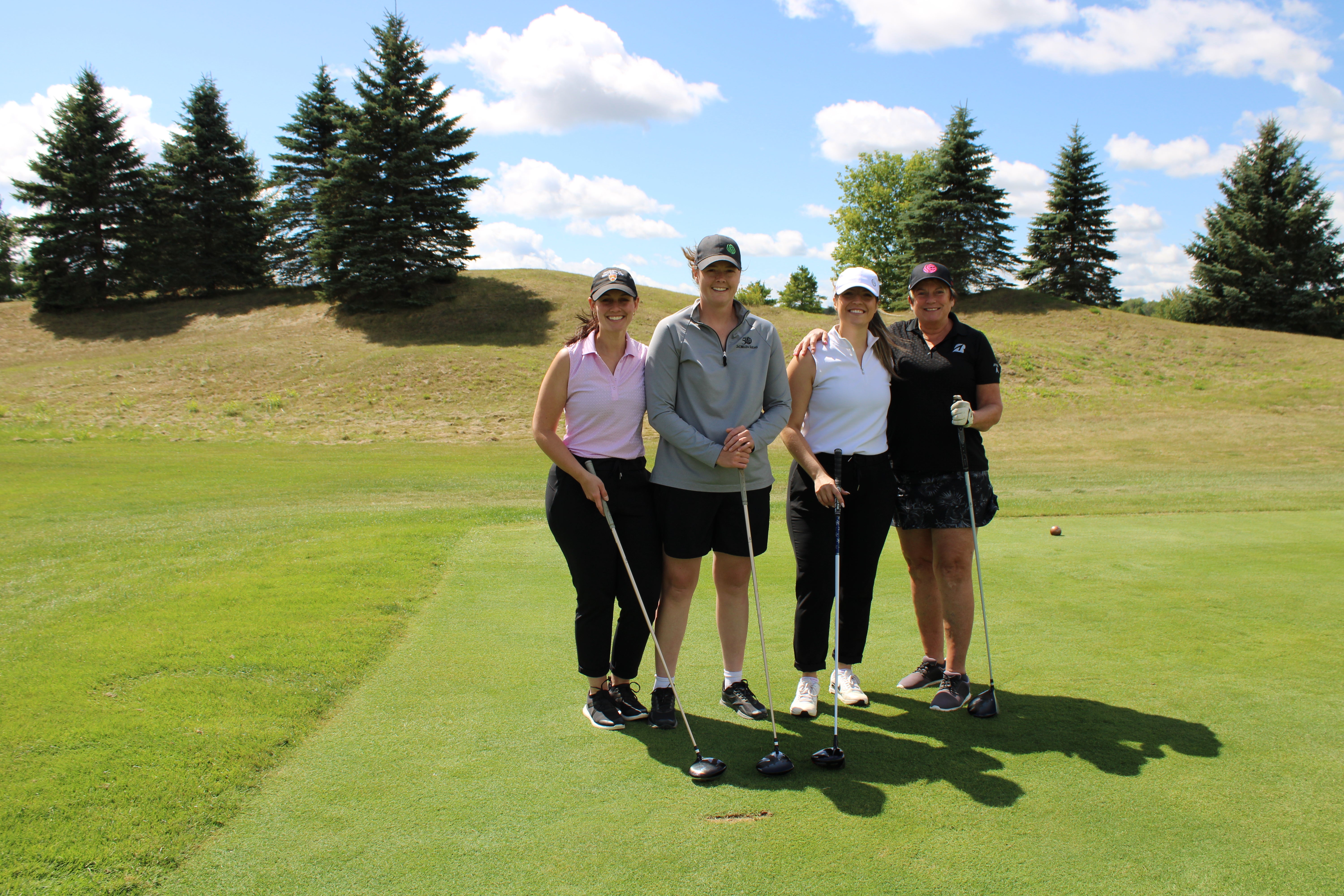 A foursome of women on the golf course smiling