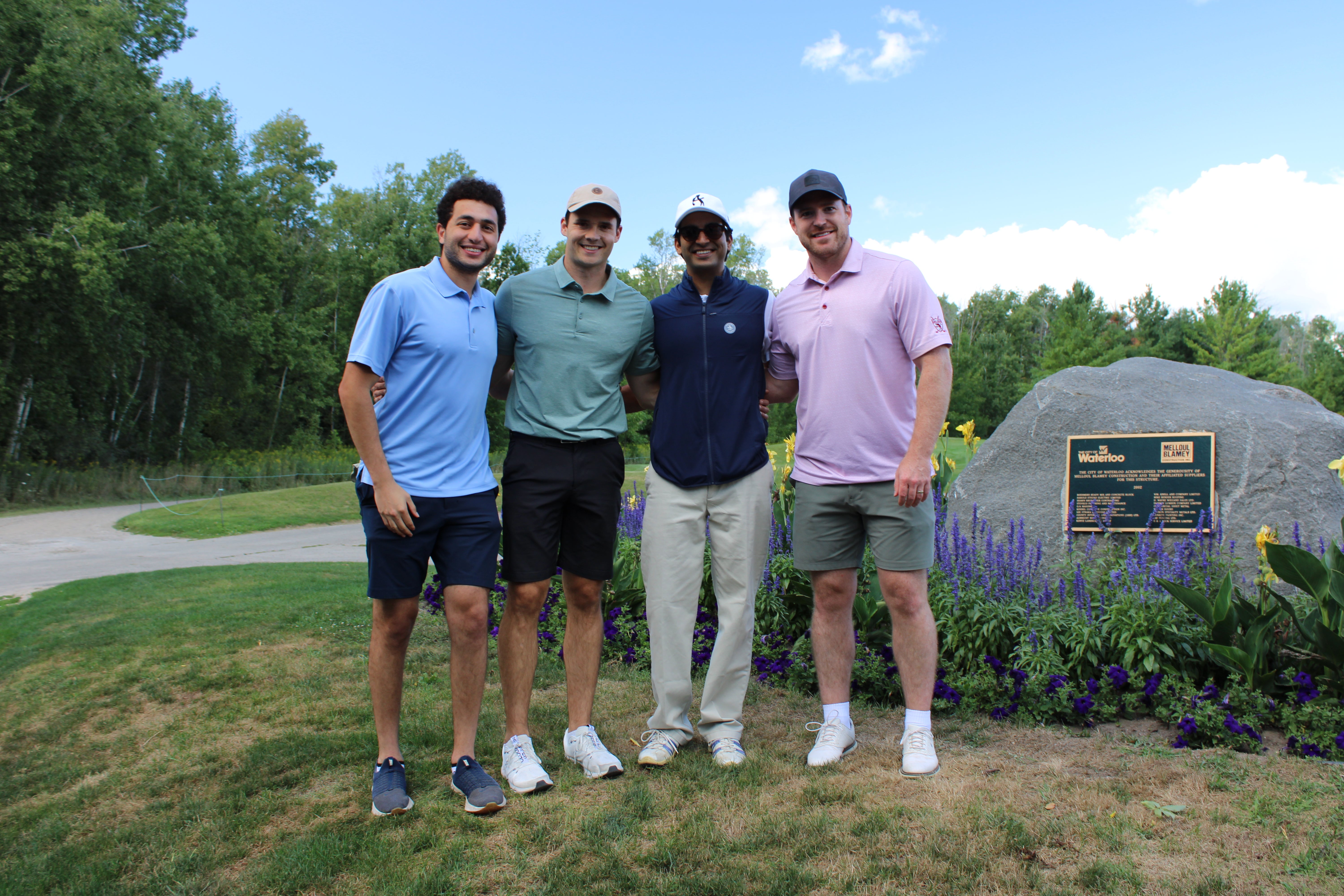 A foursome of men on the golf course smiling