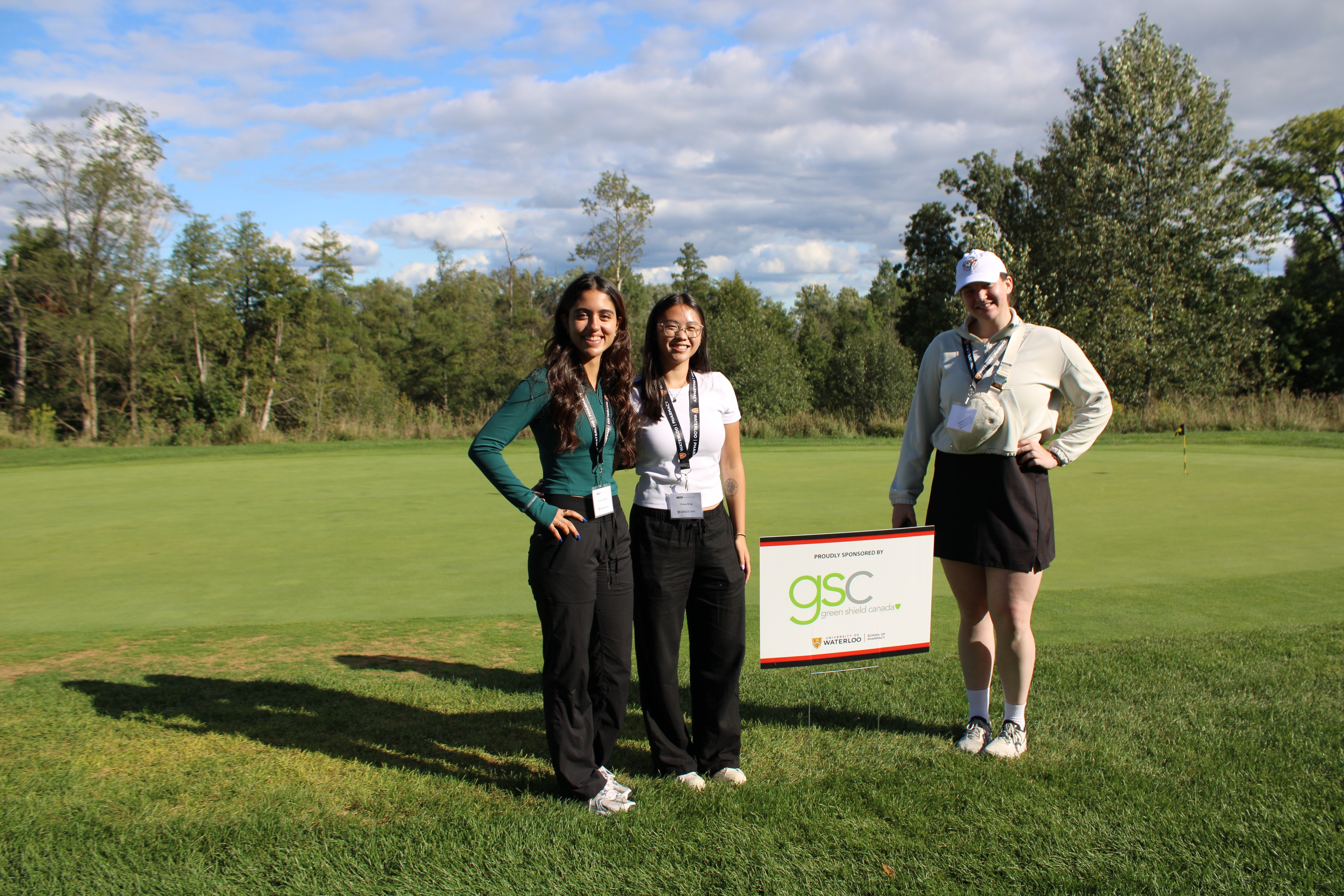 Students standing on a golf course smiling