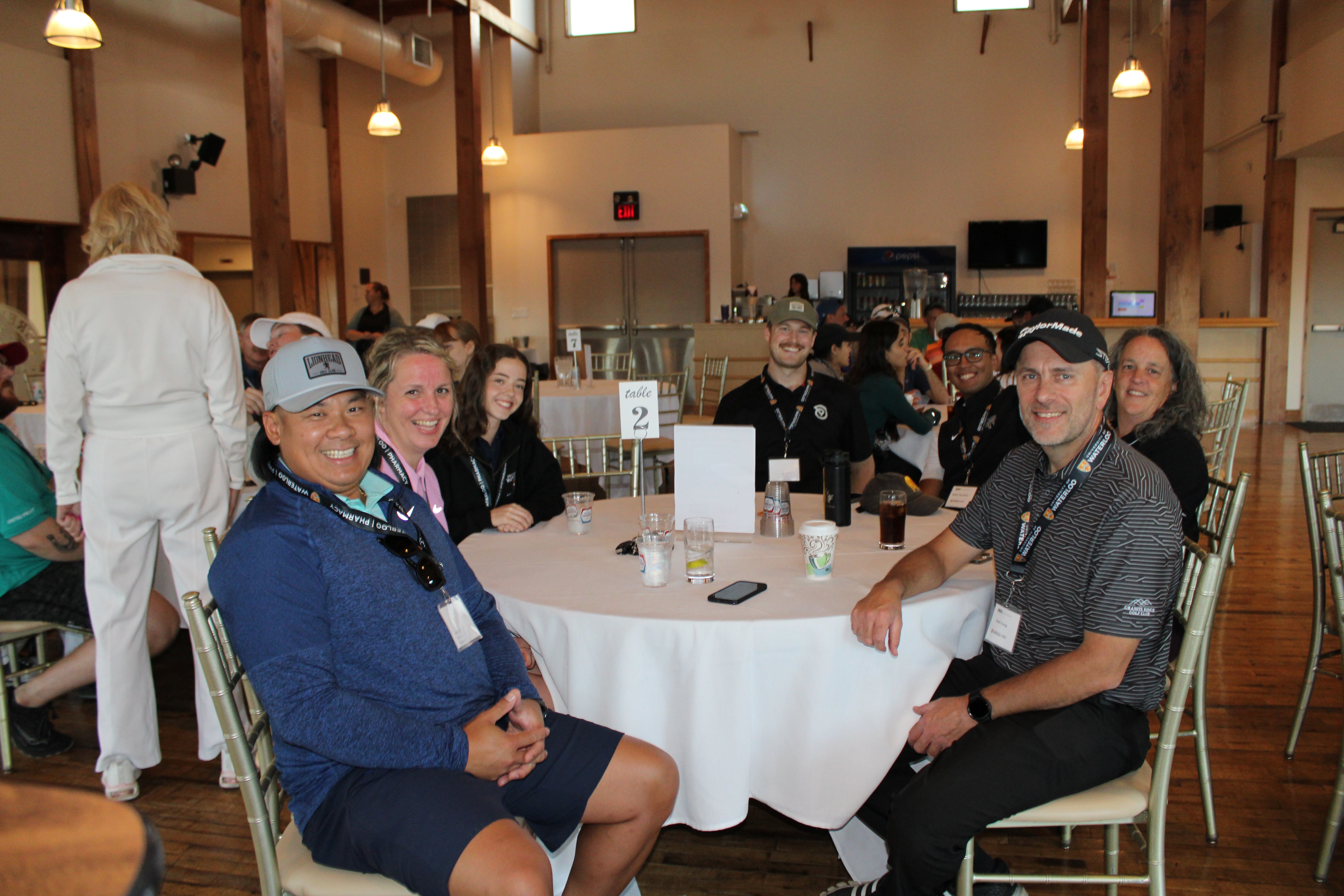 A group of people sitting around a table smiling