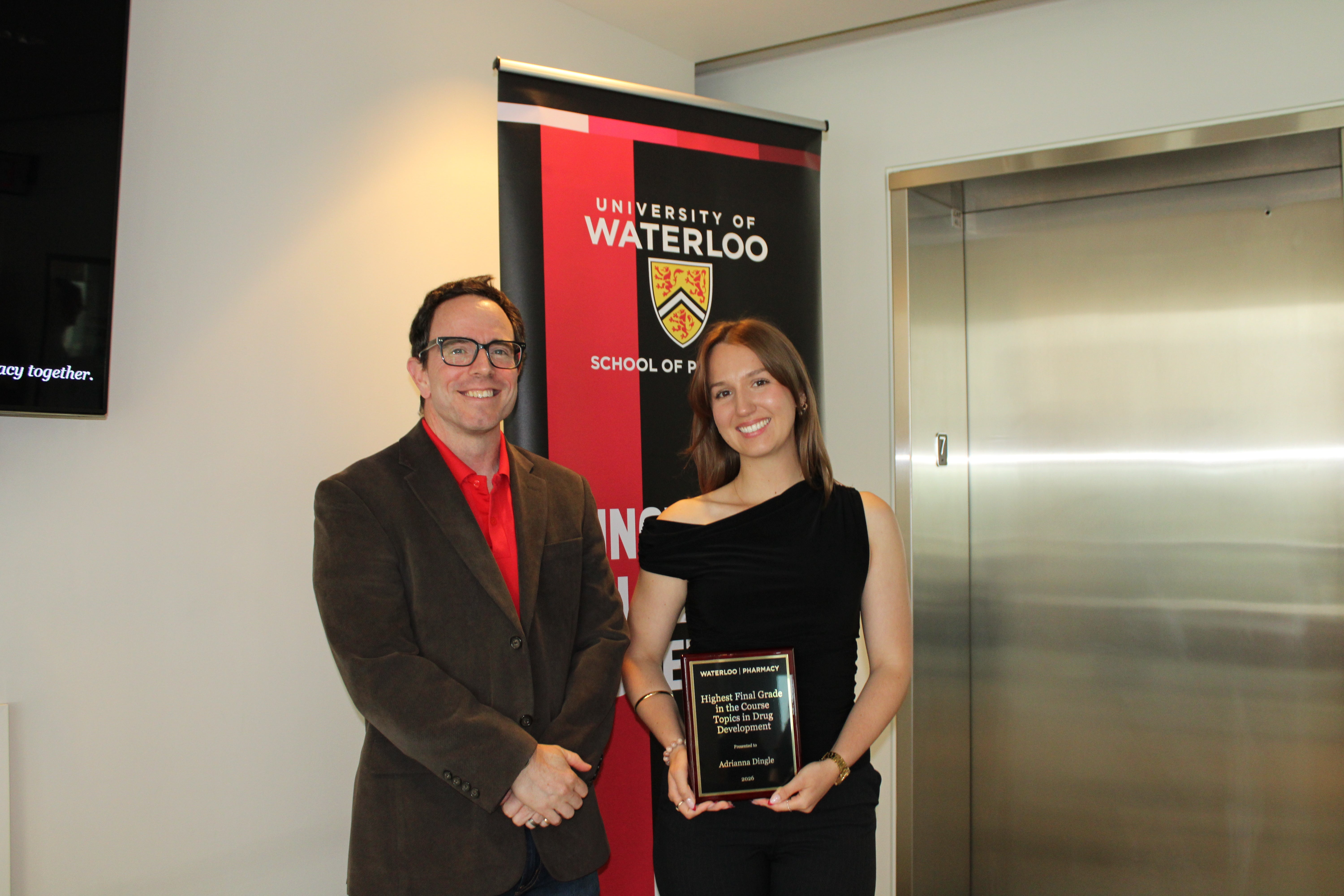 A student holding an award with a faculty member