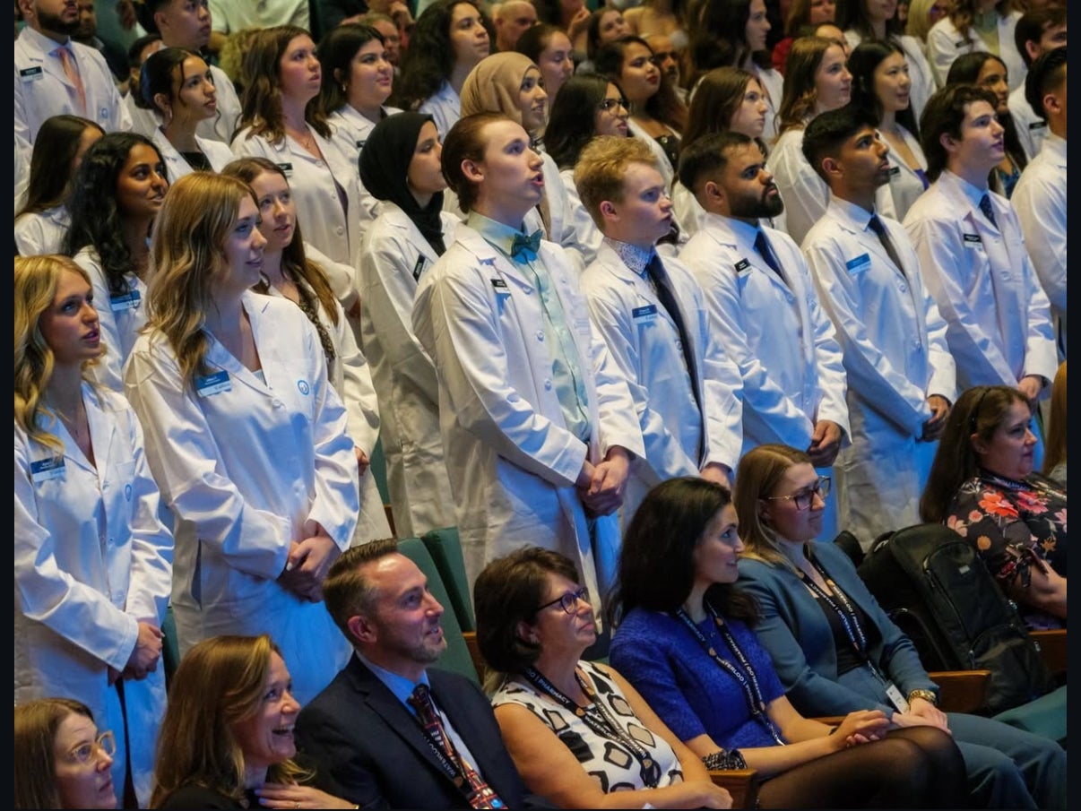 Students reciting a pledge in white coats