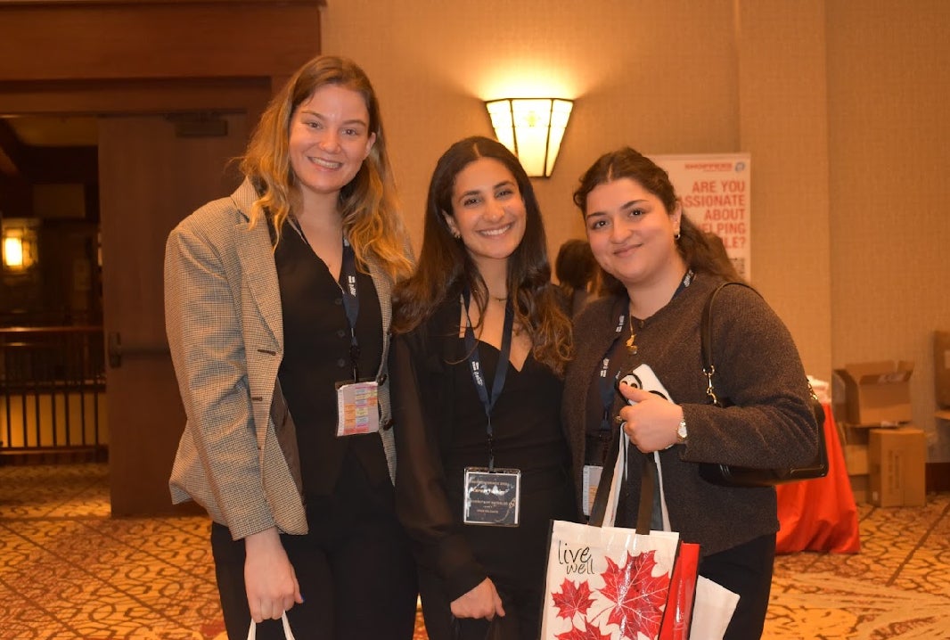 A group of women smiling holding bags at a conference