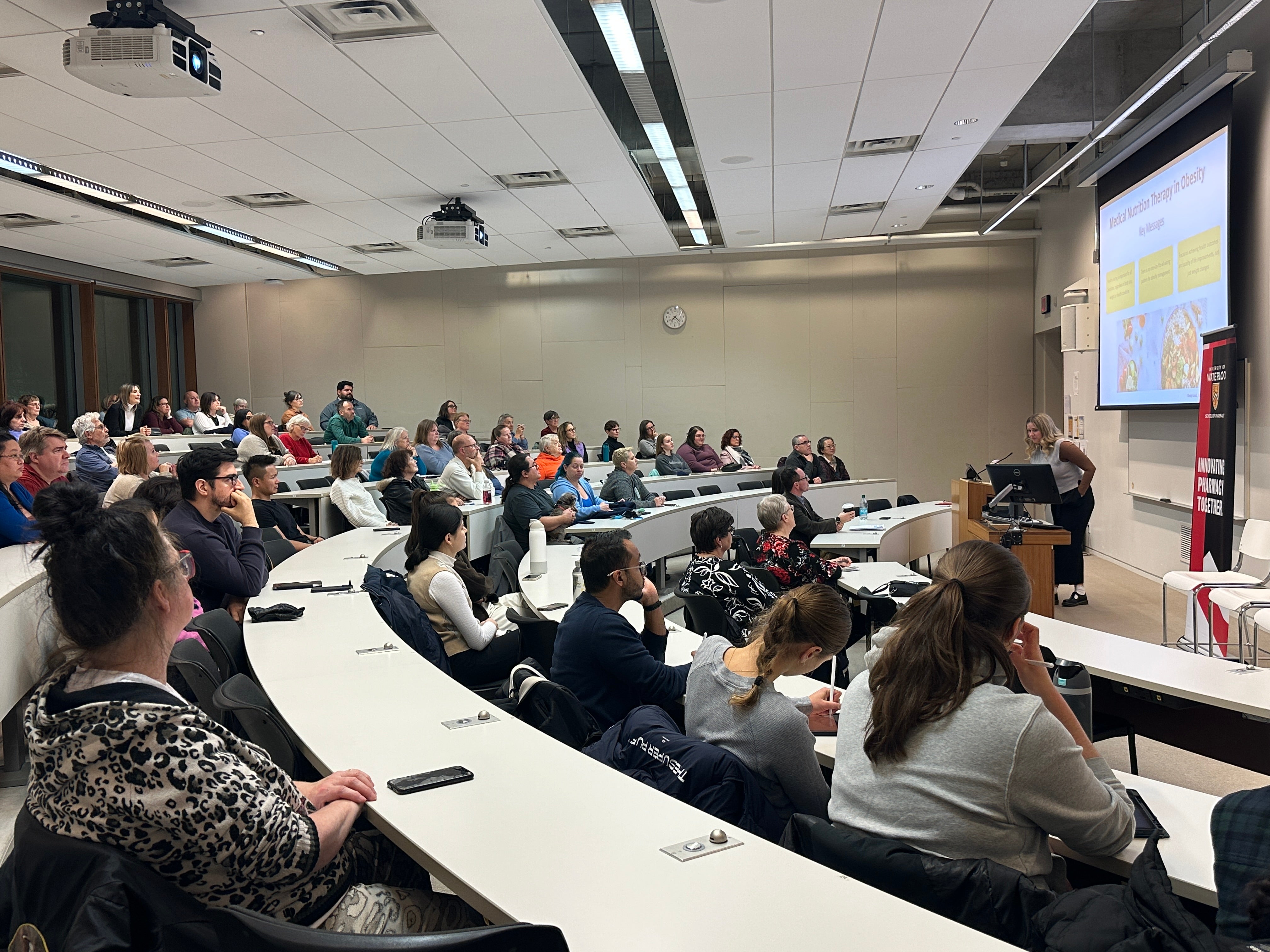 A classroom full of people listening to a presentation
