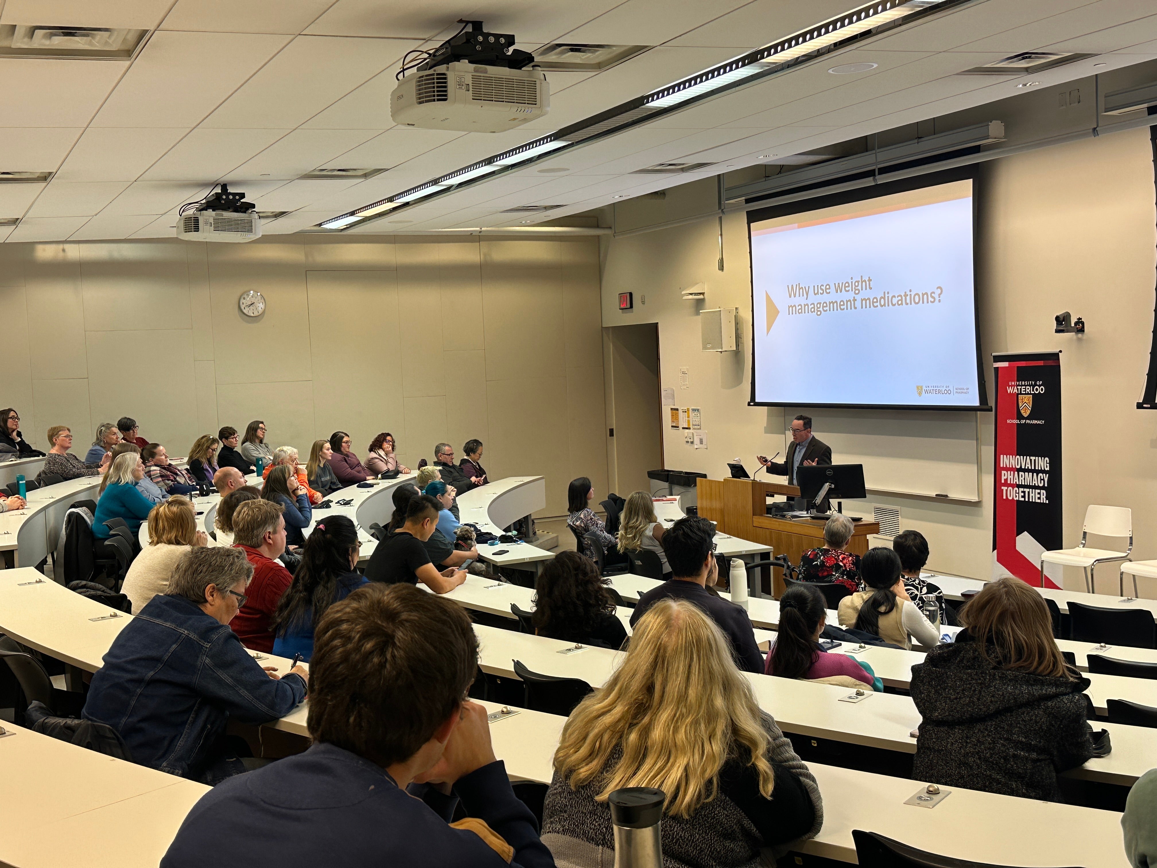 A classroom full of people listening to a presentation