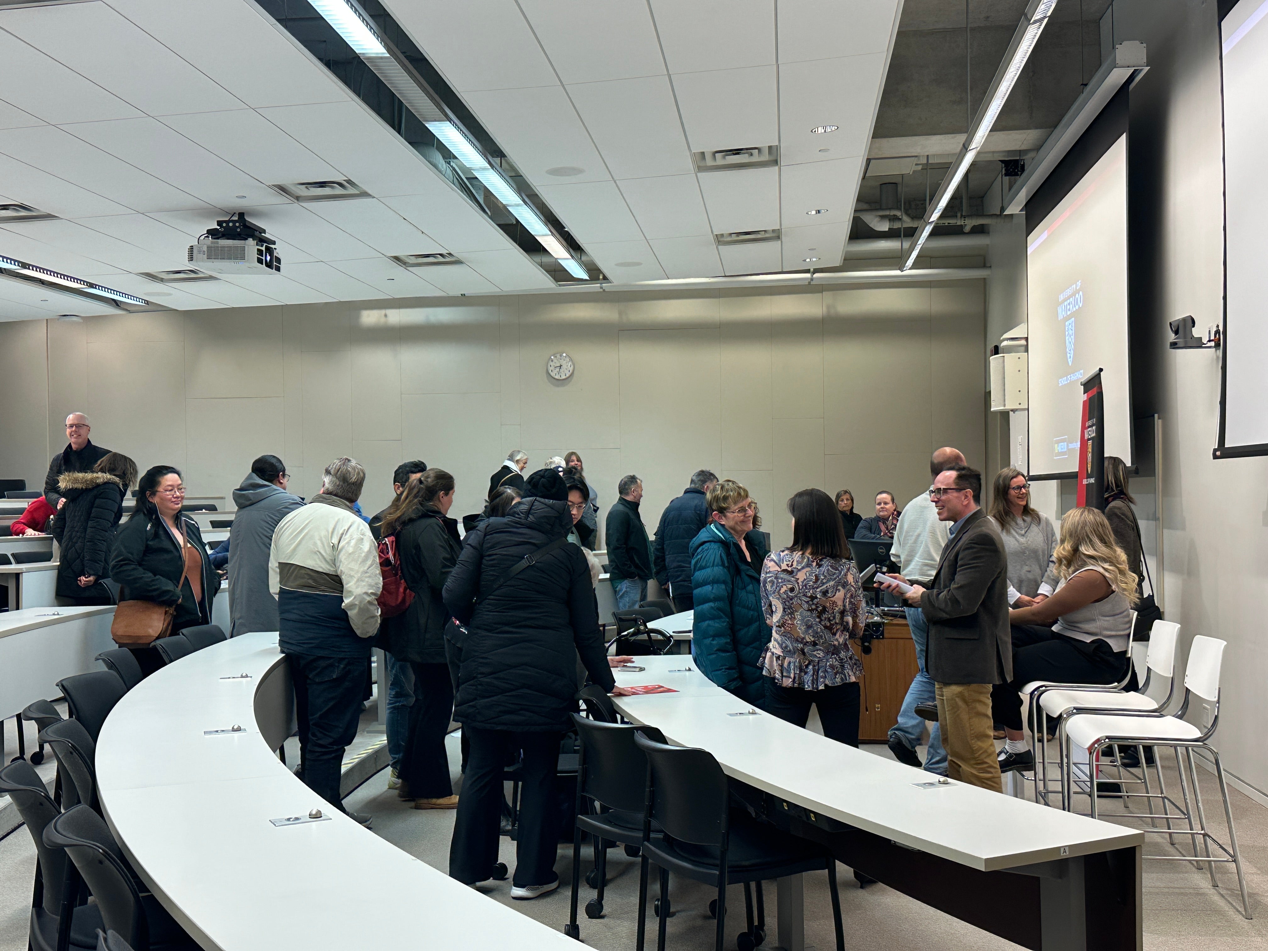 People lining up to ask presenters question in a classroom