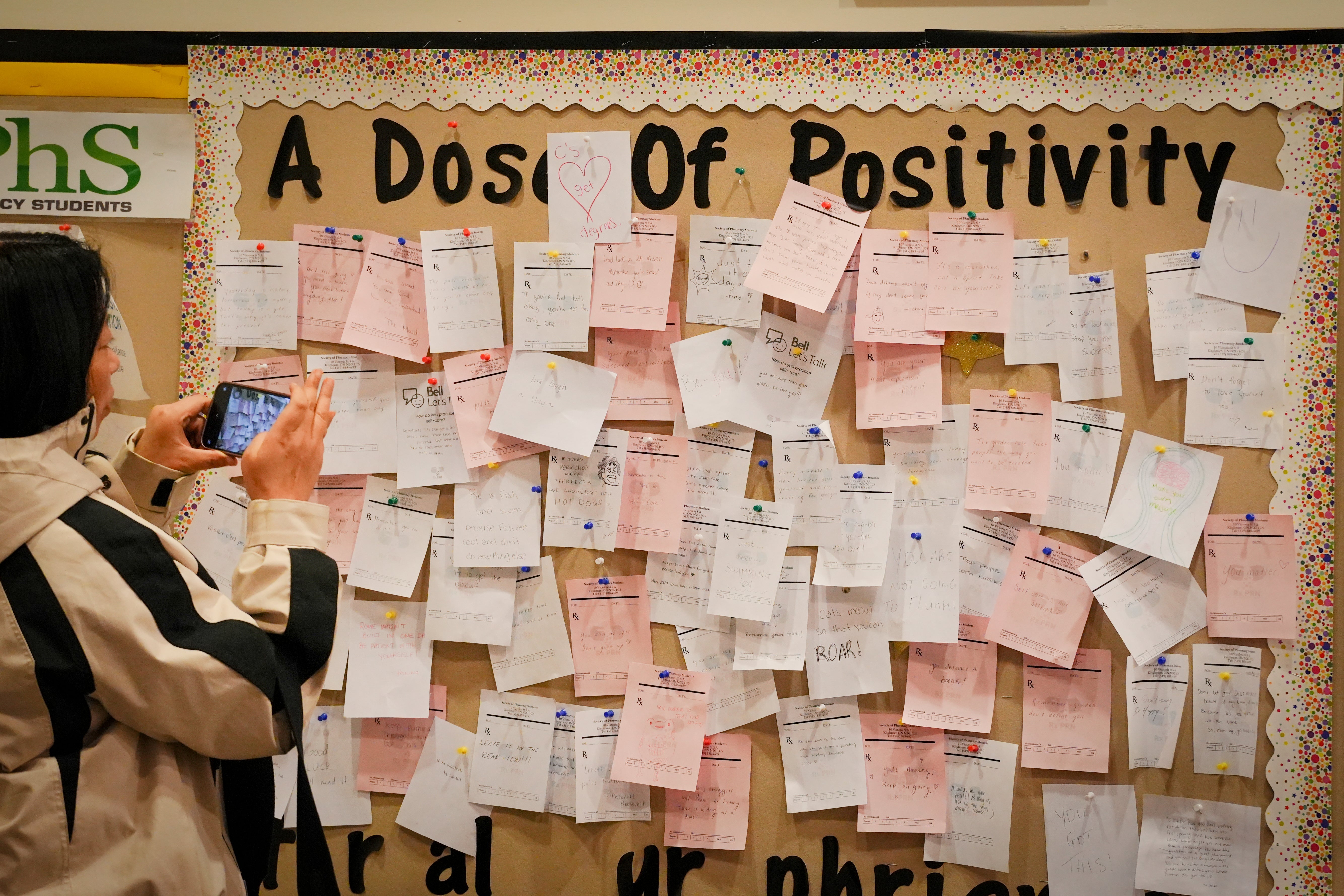 Woman takes photo of bulletin board filled with positive messaging