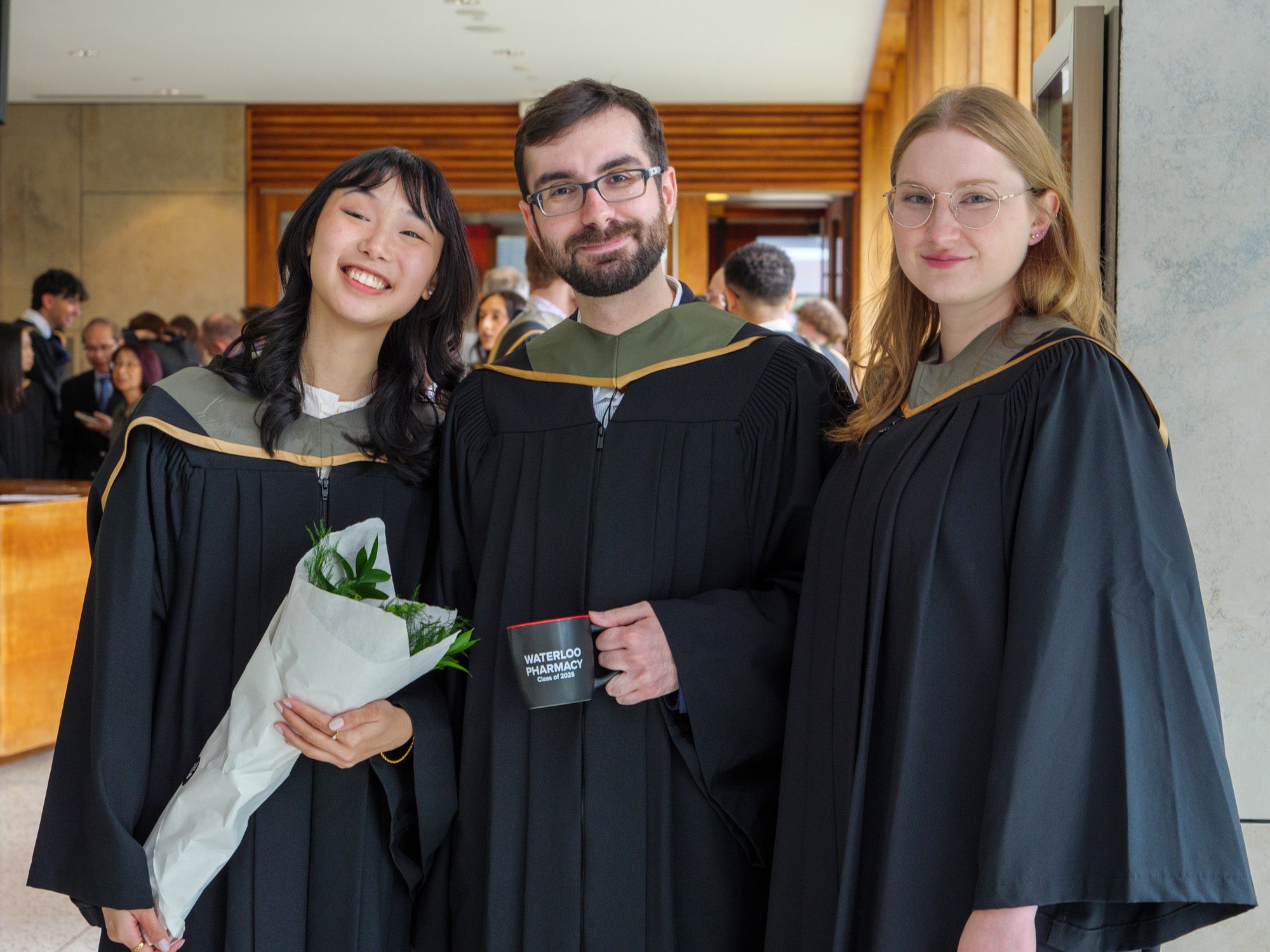 Three students smiling in their graduation robes
