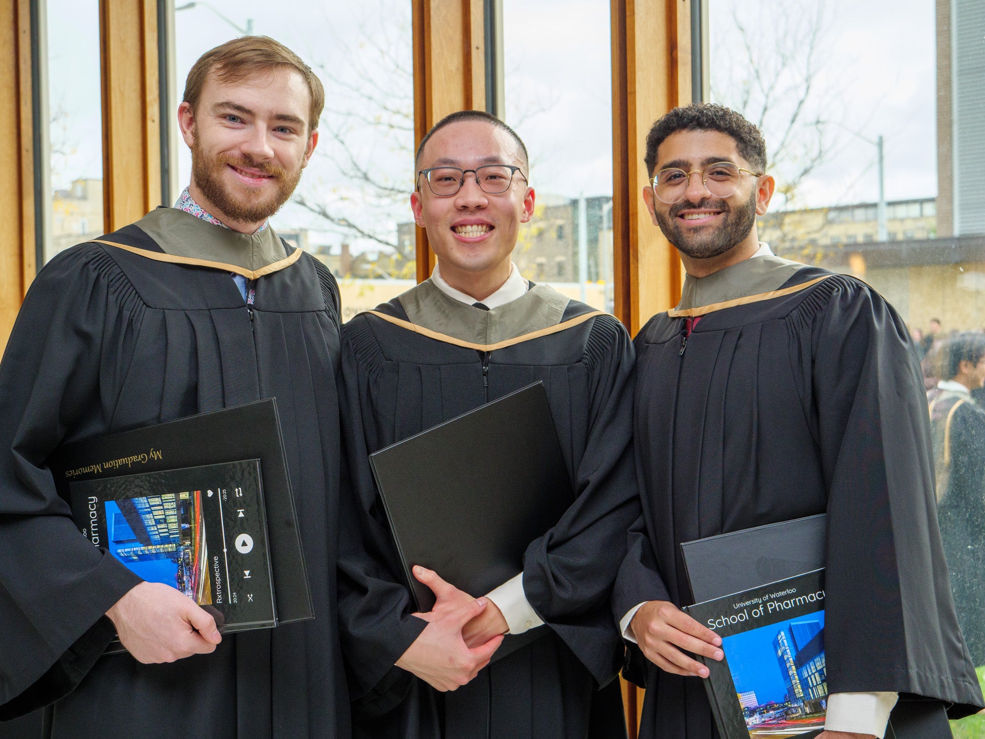 A group of men smiling in their graduation robes