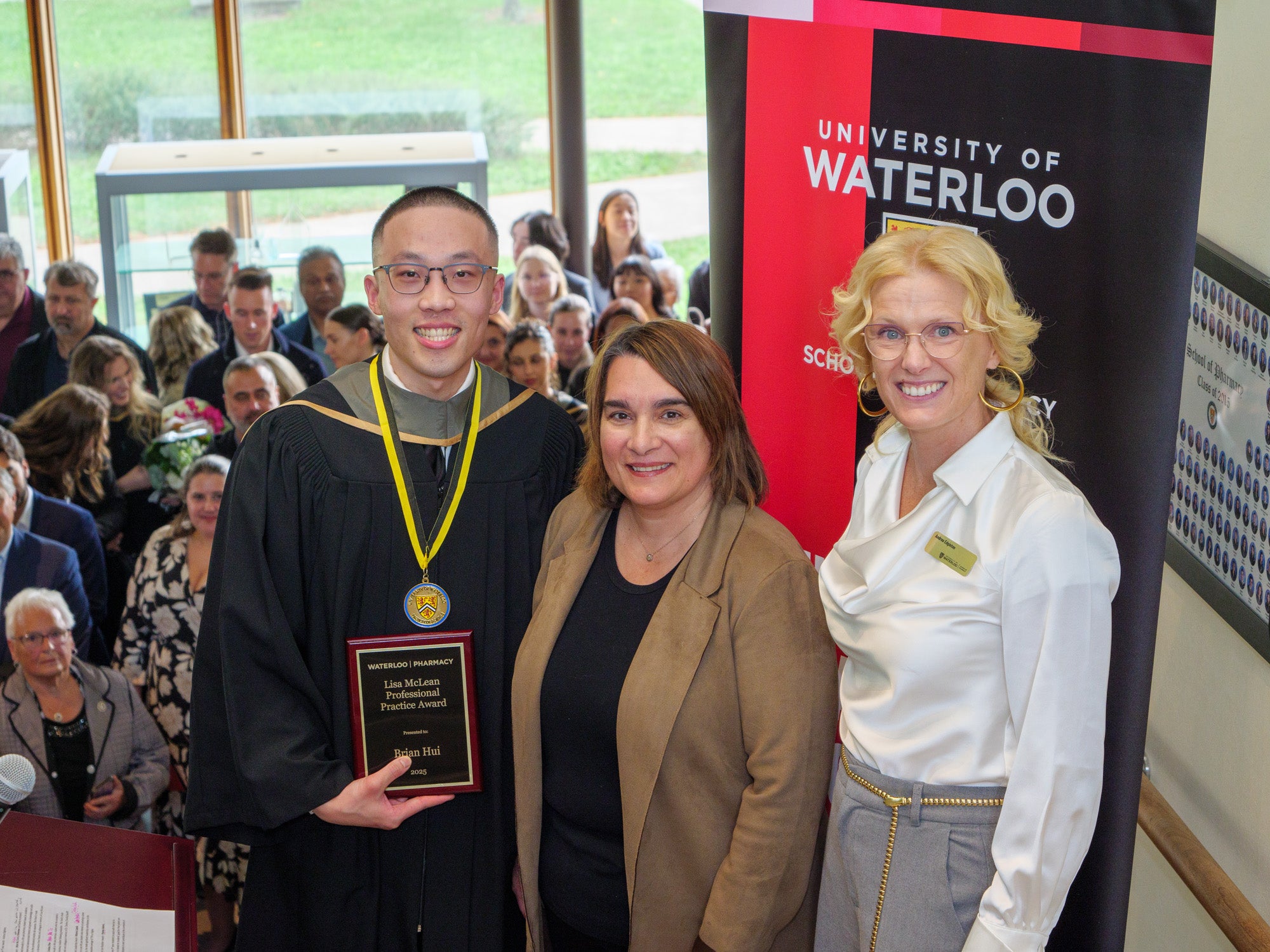 A student holding an award next to the award givers