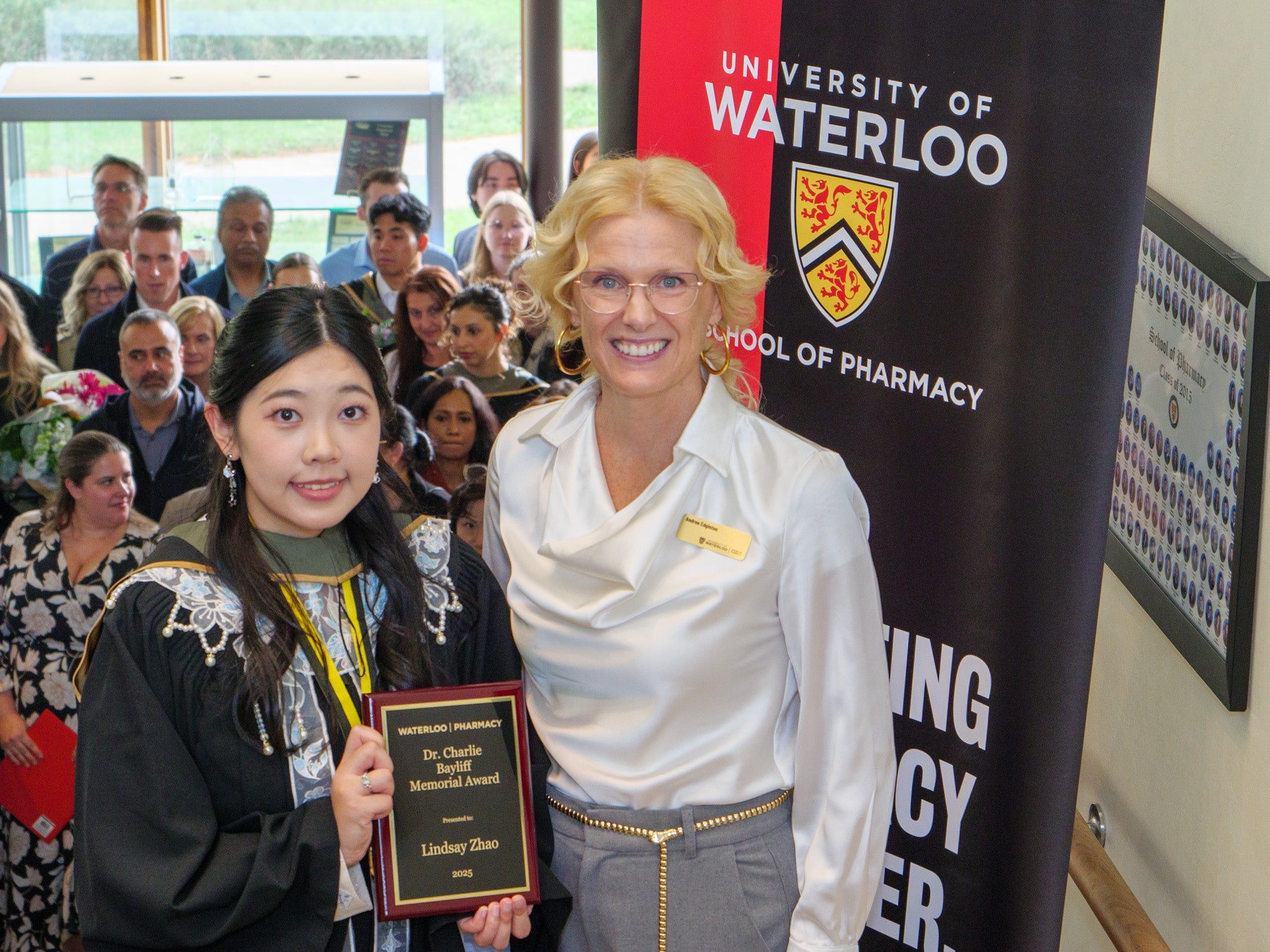 A student holding an award next to the director