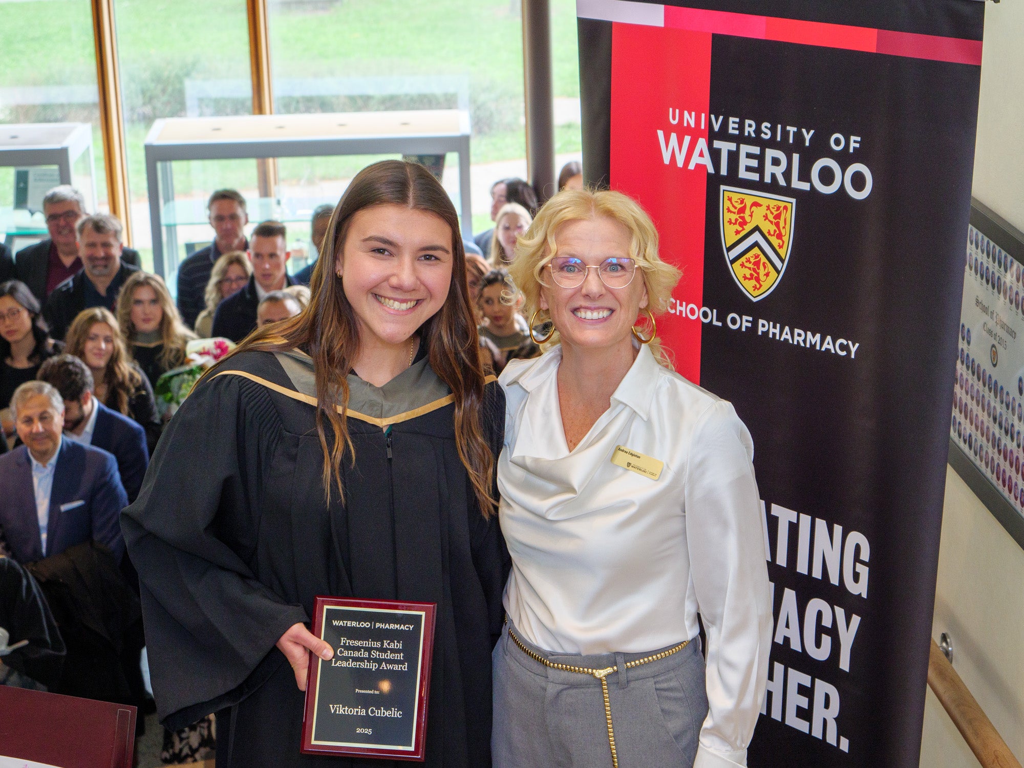 A student holding an award next to the director