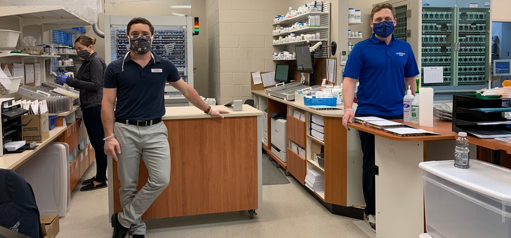 Peter and Paul standing in their pharmacy wearing masks