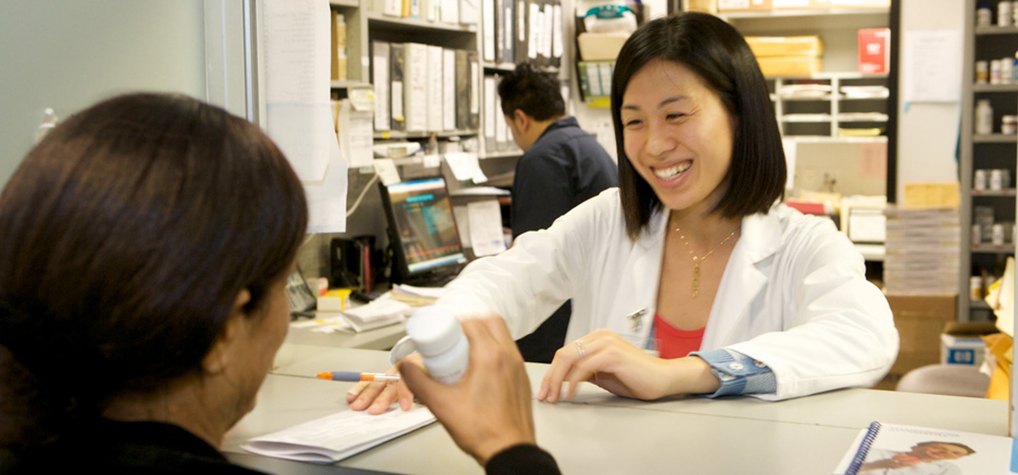 Pharmacist talking to patient and handing over paper