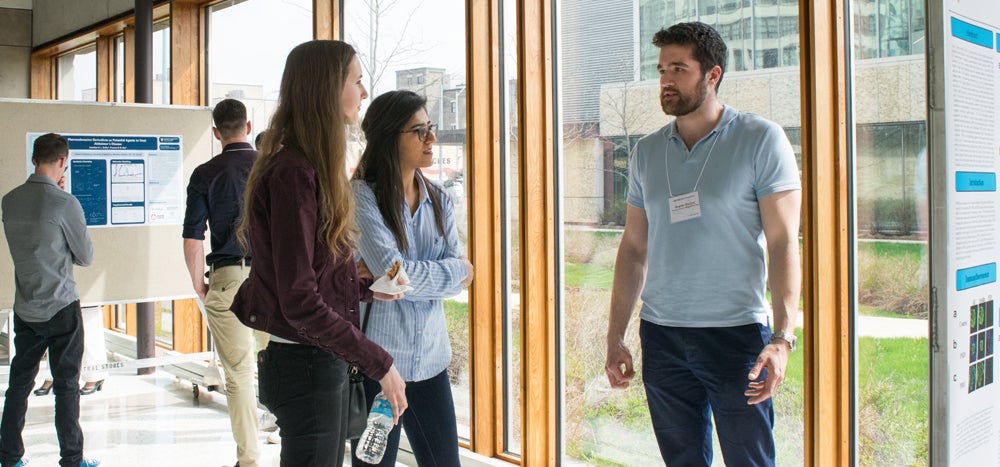 group of people talking with bulletin board in background